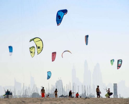 Kite beach in Jumeirah, Dubai, United Arab Emirates. A stretch of the beach designated for the kite surfers. The beach-goers are a colorful mix of different nationalities.