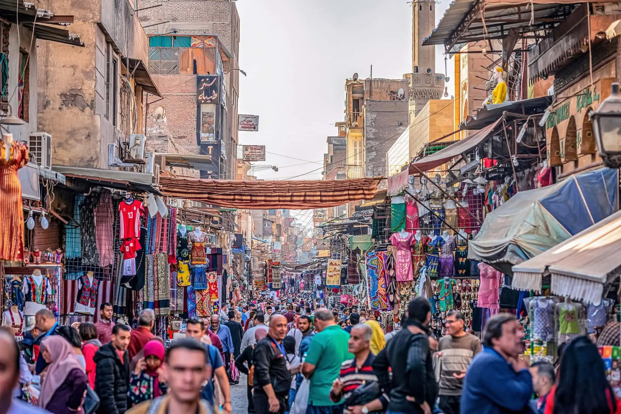 Bustling Khan el-Khalili marketplace in Cairo with people shopping at textile stalls