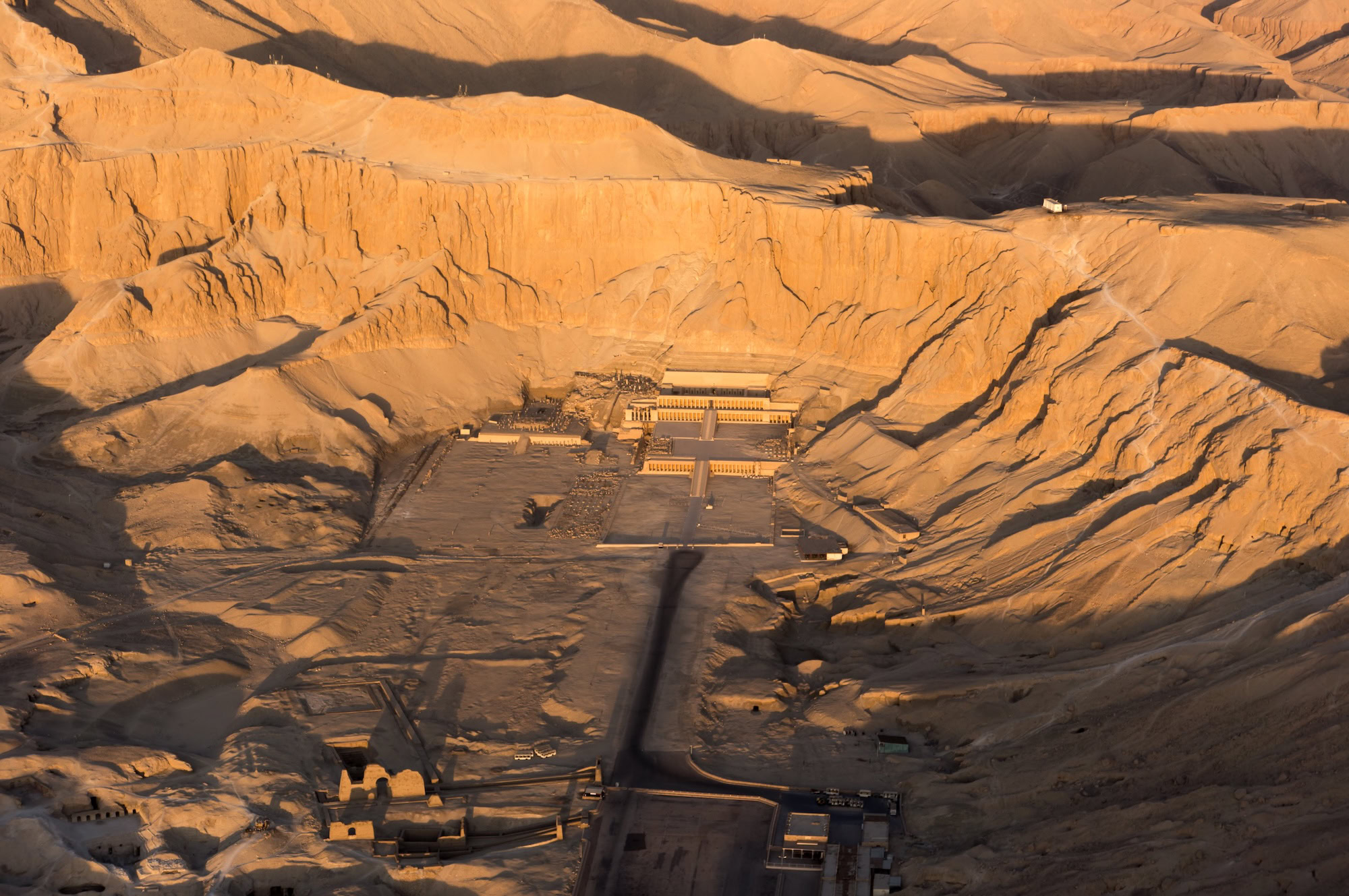 Hatshepsut Temple's terraced limestone structure nestled against dramatic cliffs in Egypt's desert valley