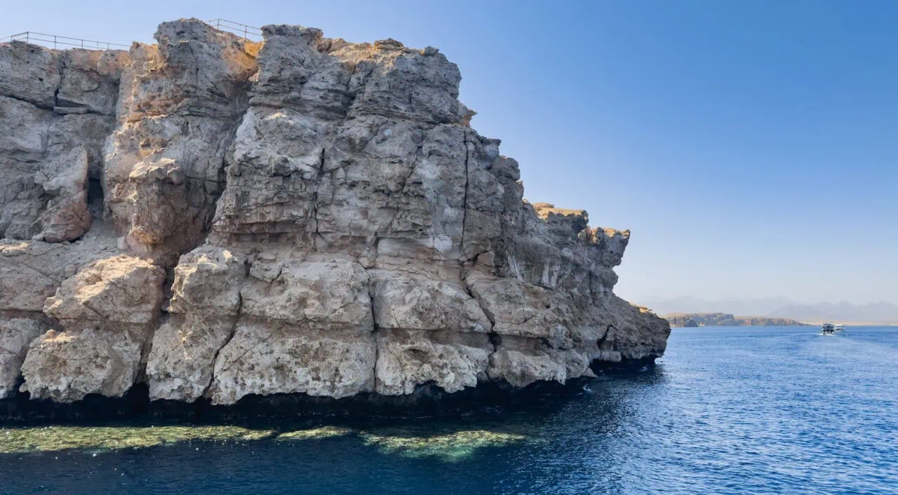 A rock formation and yachts sailing into the distance in the Gulf of Aqaba in the Ras Mohamed National Park in South Sinai