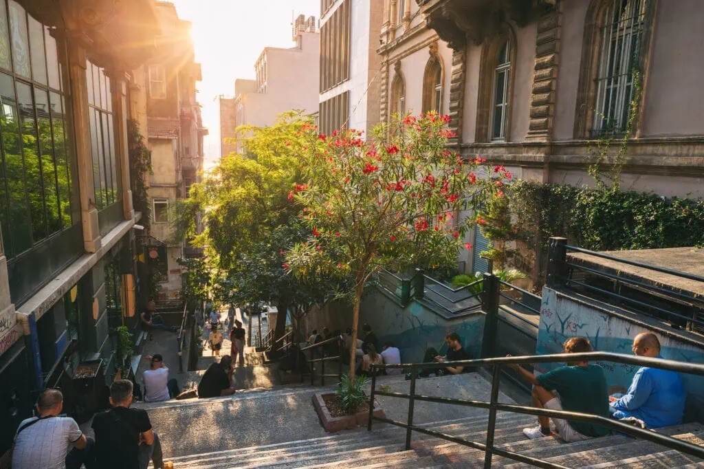 A street in Istanbul at sunset with people resting at ancient stairs in the Pera district