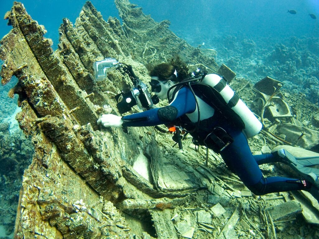 A underwater photographer taking pictures of small fish on a wreck