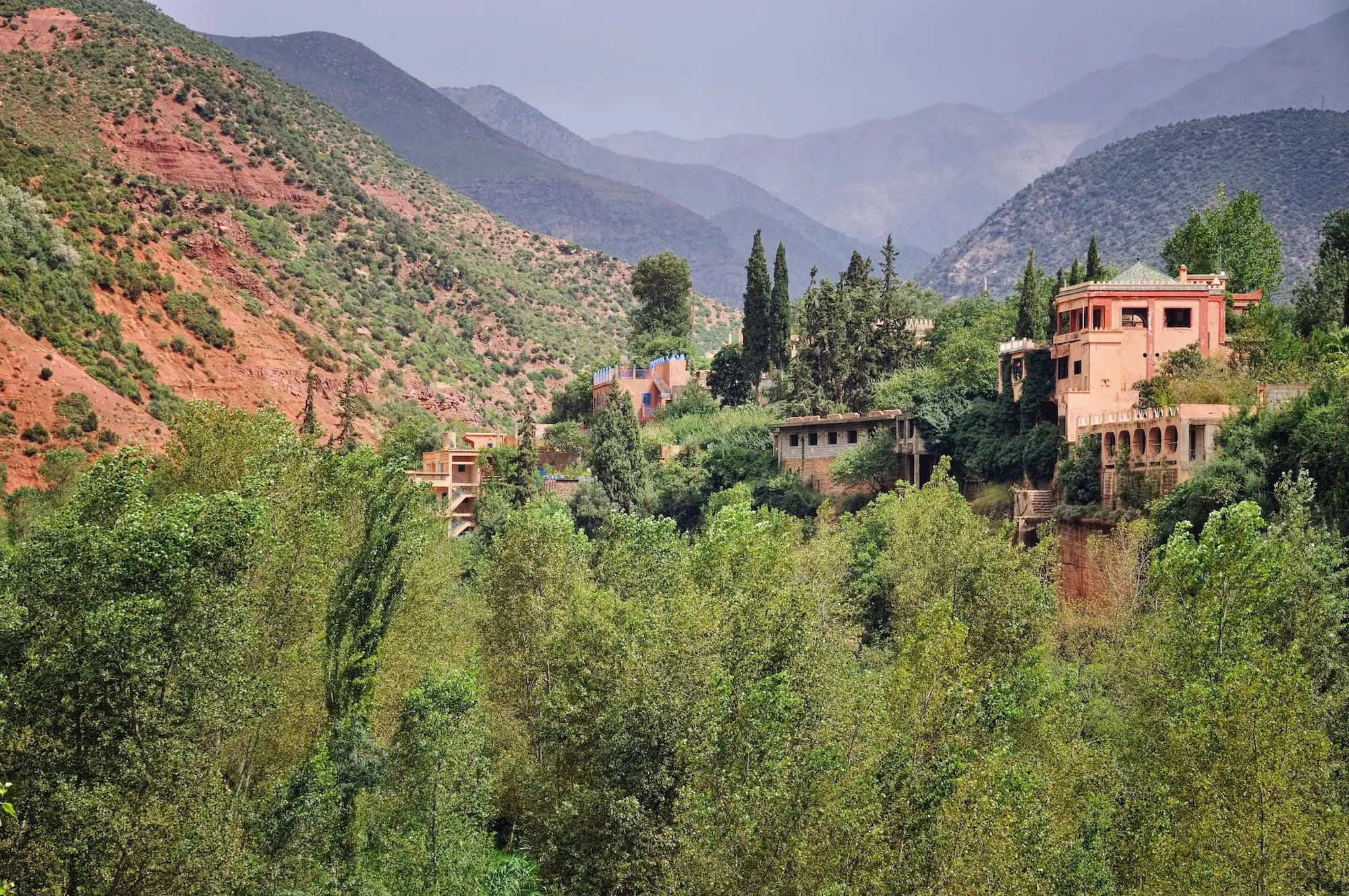 Scenic Ourika Valley landscape with traditional Moroccan buildings and Atlas Mountains backdrop