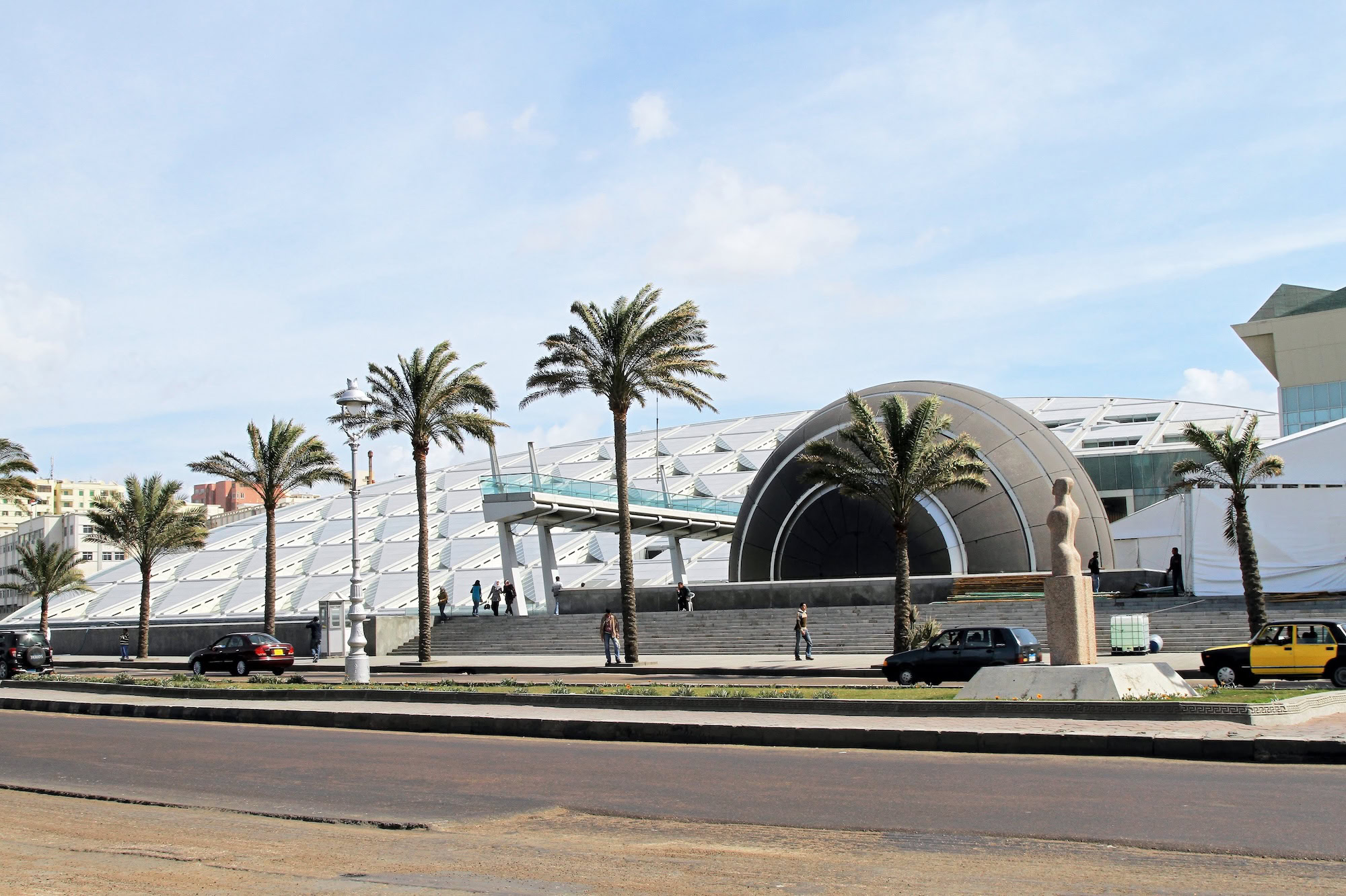 Modern Alexandria Library building with distinctive curved architecture and geometric facade surrounded by palm trees