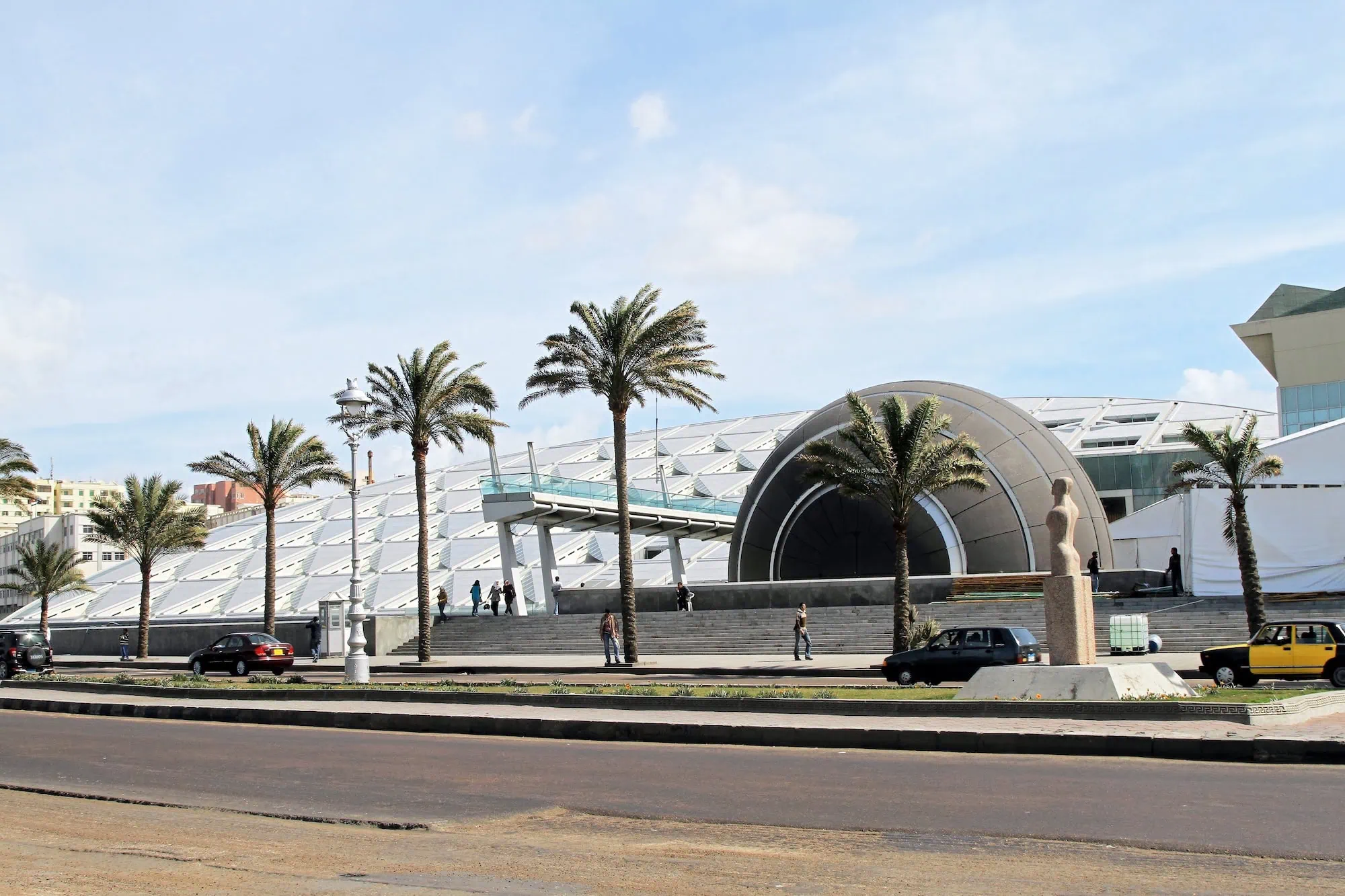 Modern Alexandria Library building with distinctive curved architecture and geometric facade surrounded by palm trees