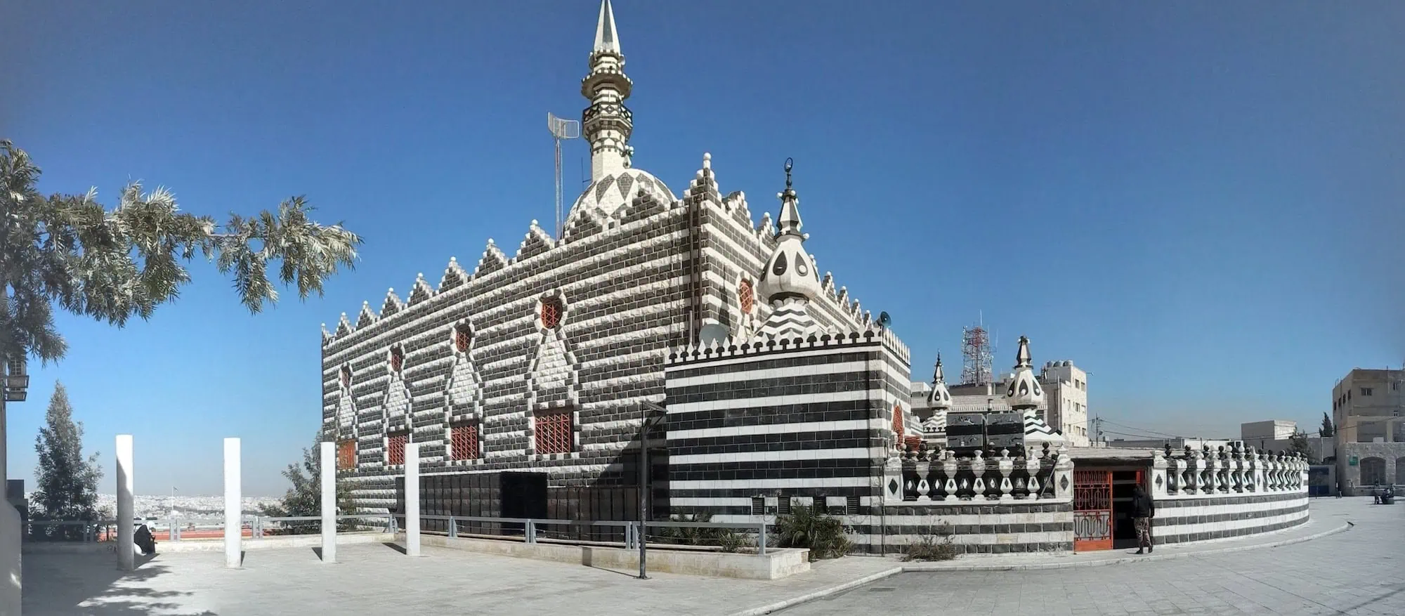 Black and white striped Abu Darweesh Mosque in Amman, Jordan with minaret and city view