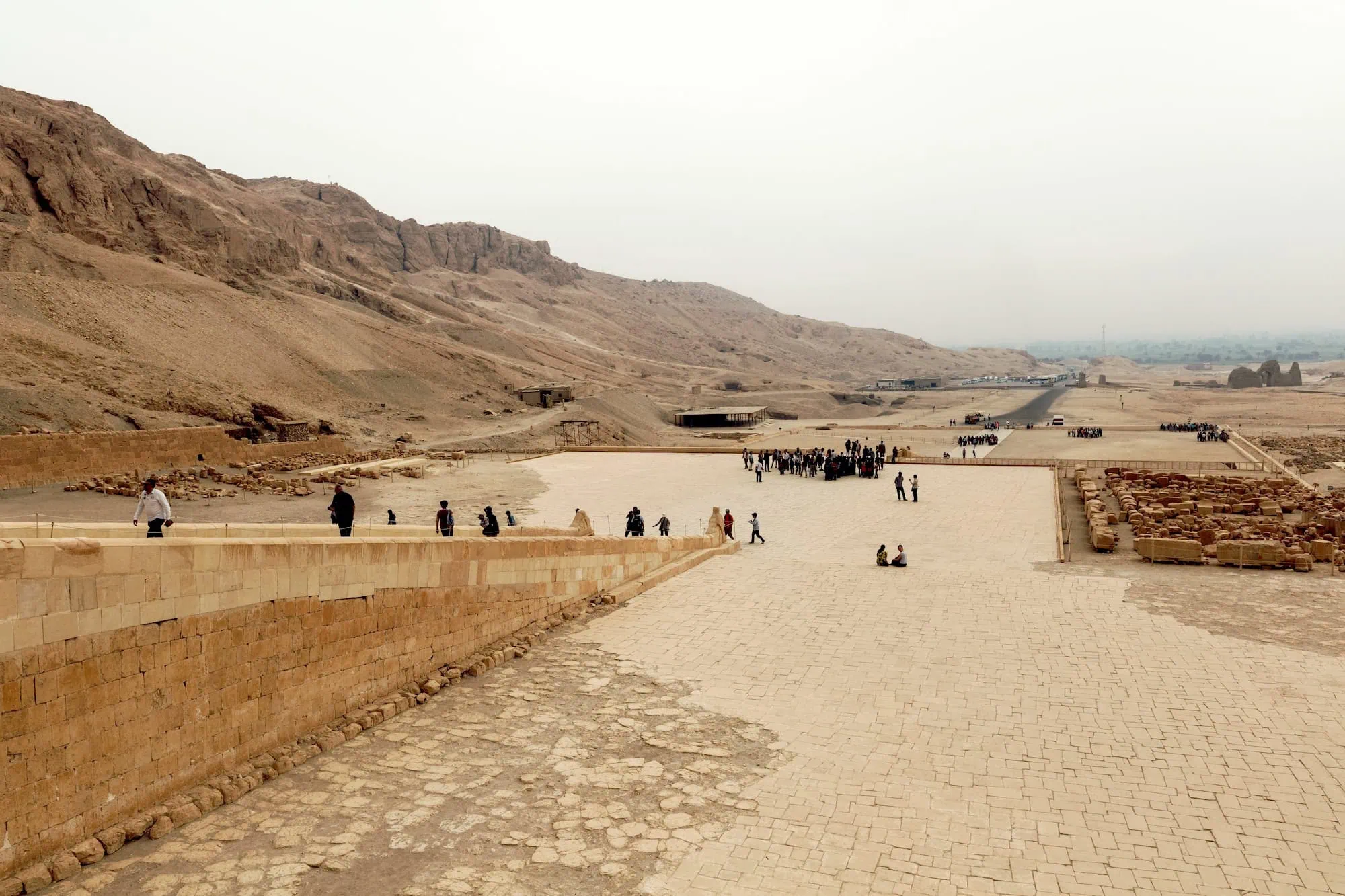Turistas caminando por sitio arqueológico con murallas de piedra antigua