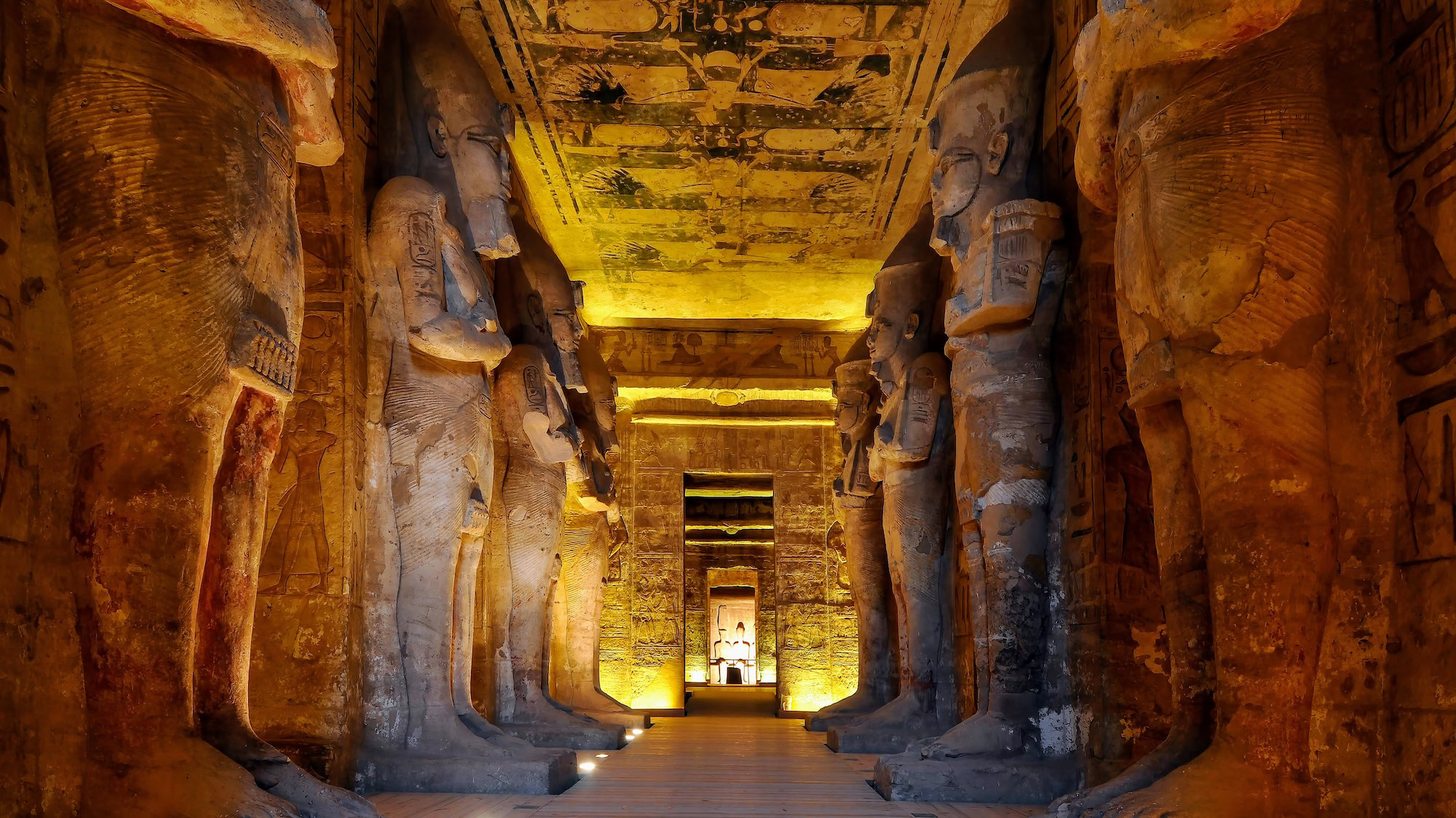 Interior of Abu Simbel temple showing seated statues of Ramesses II as god Osiris with hieroglyphic carvings