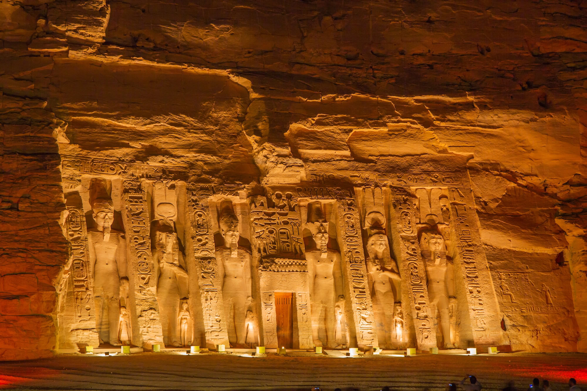 Abu Simbel temple complex illuminated at night with golden lighting on ancient Egyptian statues