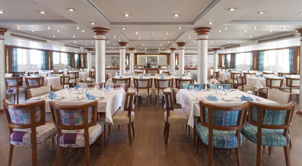 Fine dining restaurant aboard MS Amarco with set tables, interior seating, and views overlooking the Nile River, Luxor