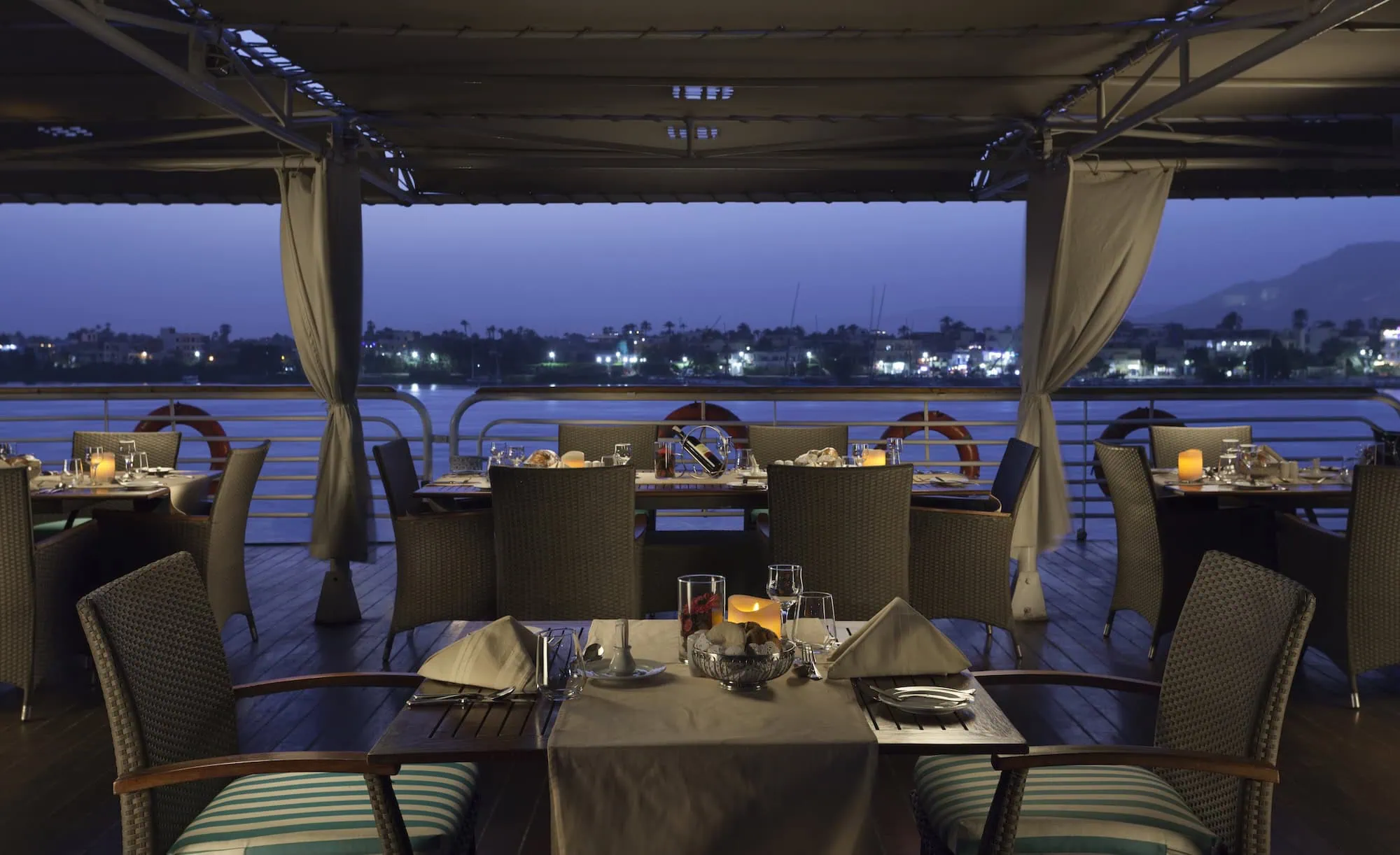 Restaurante elegante en crucero del Nilo con mesas preparadas y vista al río