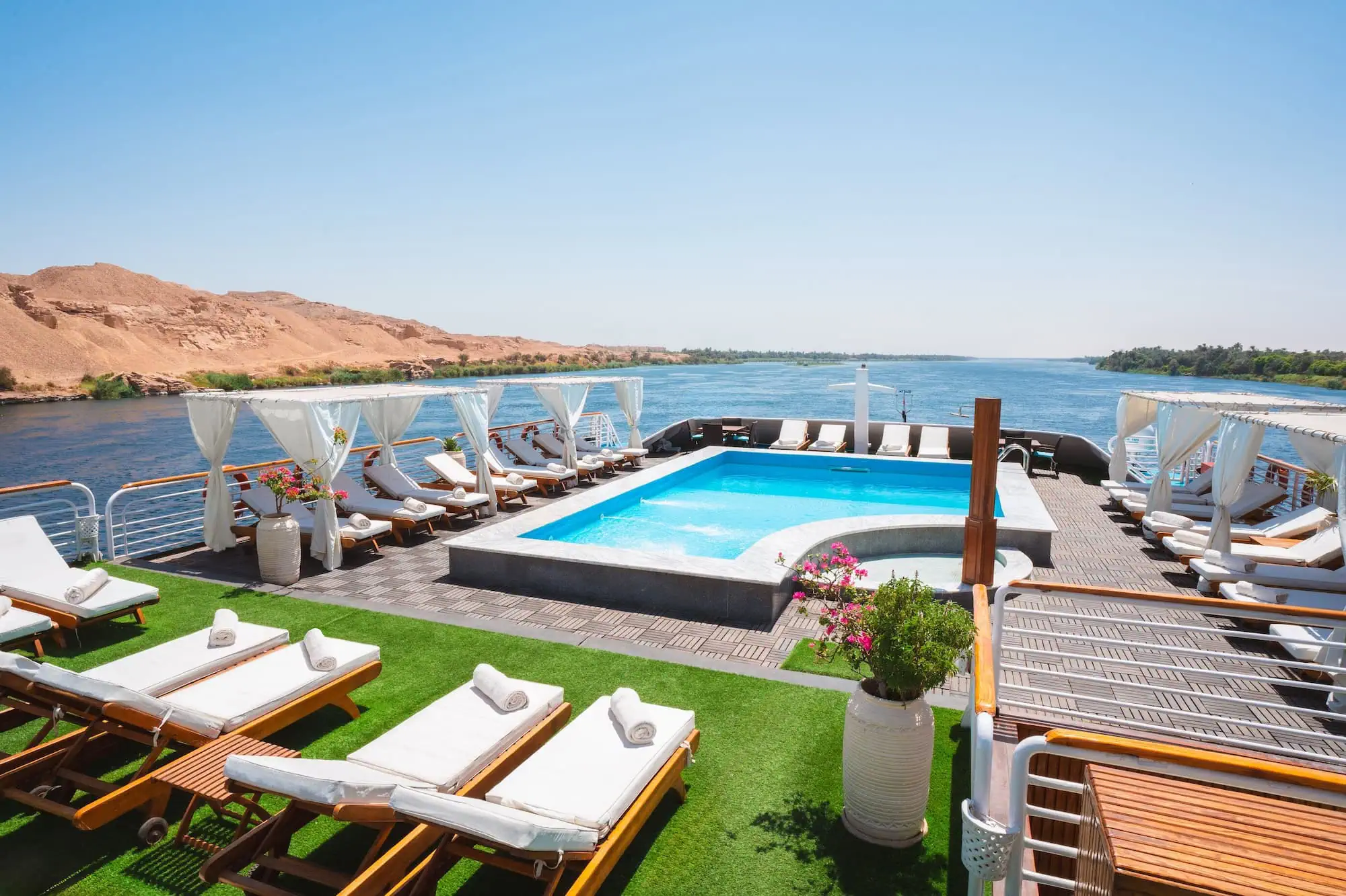 Luxury Nile cruise ship pool deck with lounge chairs overlooking desert hills