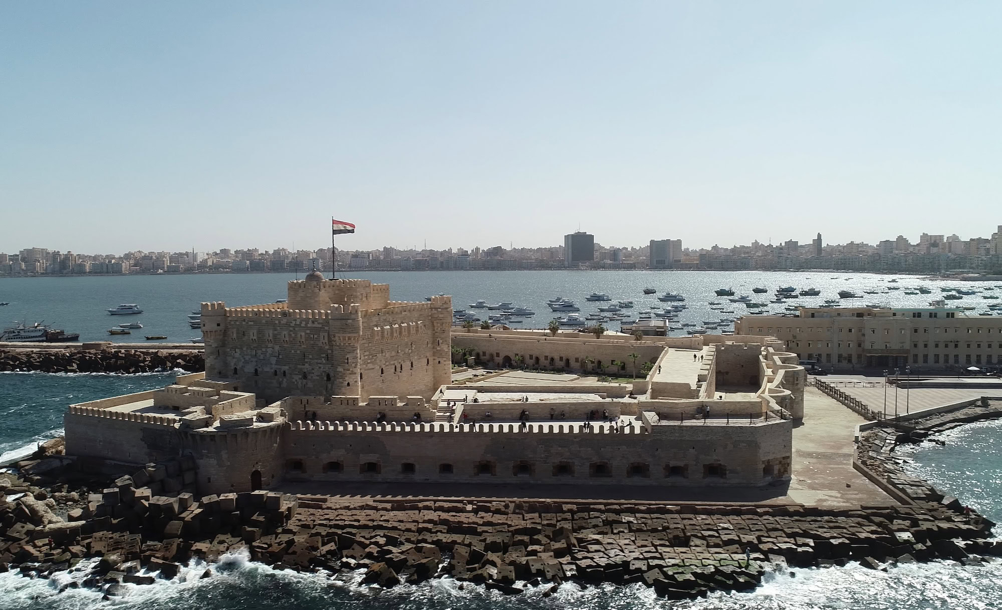 Historic Qaitbay Citadel fortress overlooking Alexandria harbor with boats and cityscape