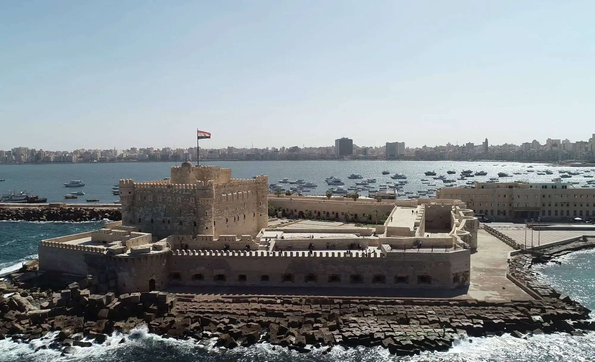 Historic Qaitbay Citadel fortress overlooking Alexandria harbor with boats and cityscape