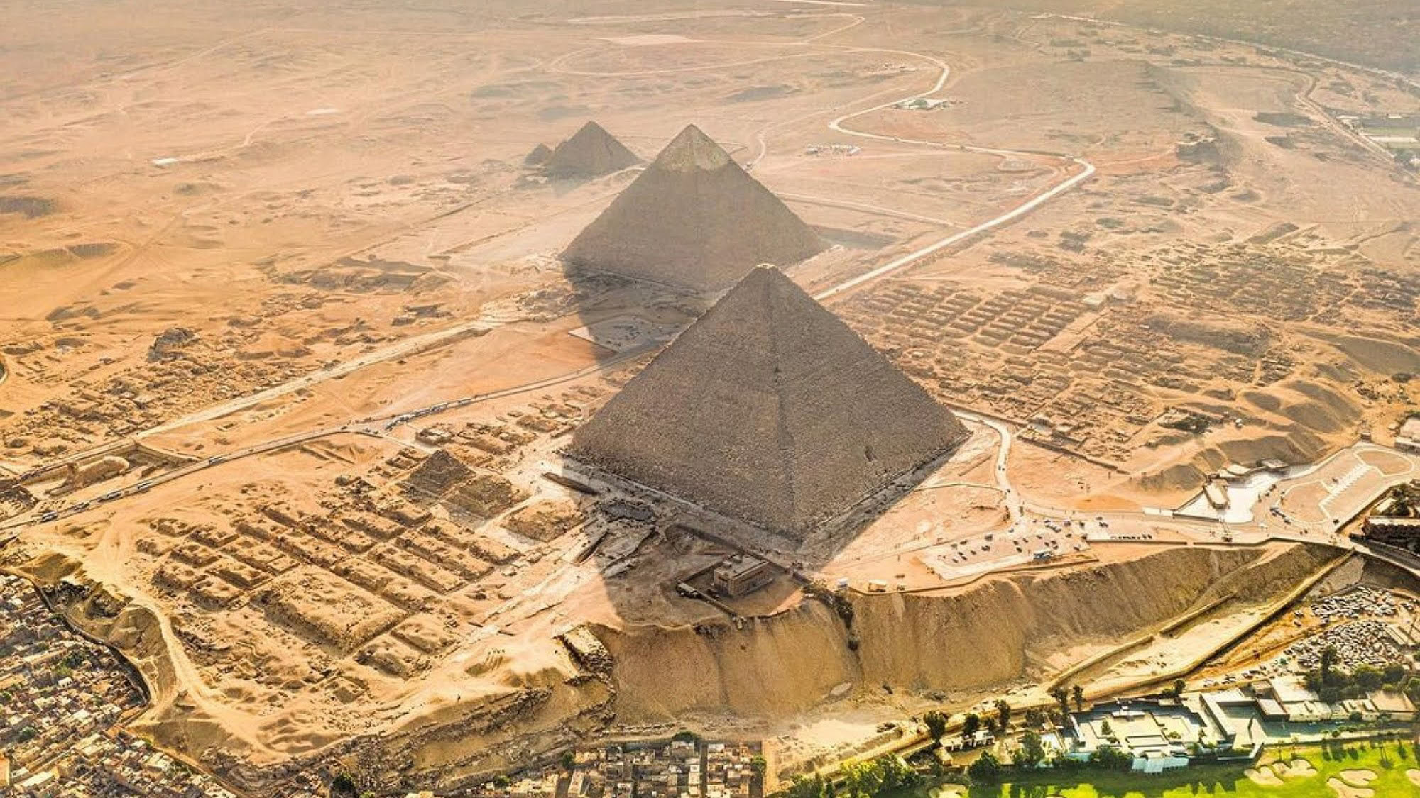 Aerial view of the Great Pyramids of Giza showing the ancient pyramids surrounded by modern urban development and roads