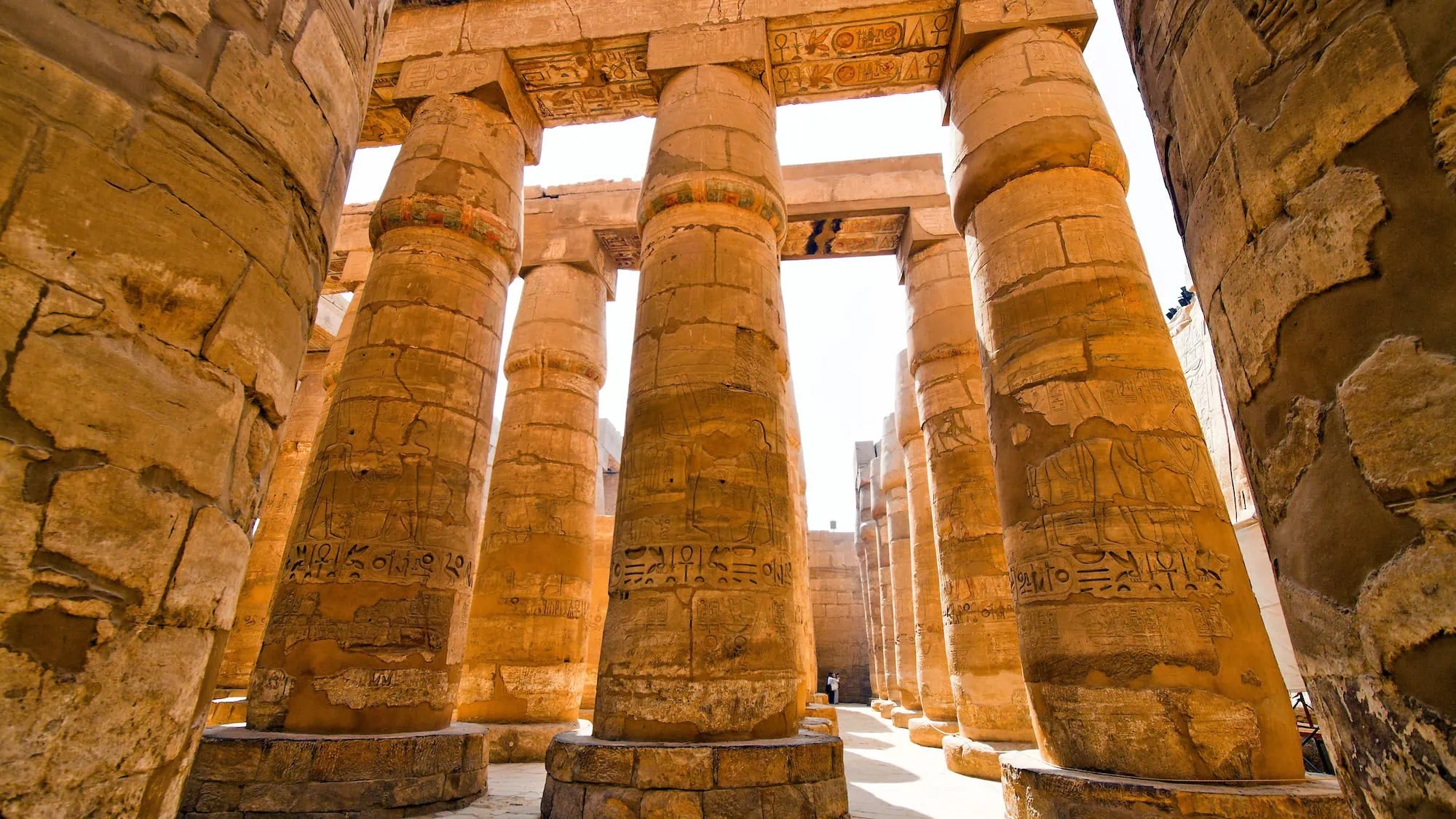 Interior view of Karnak Temple's Hypostyle Hall showing massive stone columns with hieroglyphic carvings