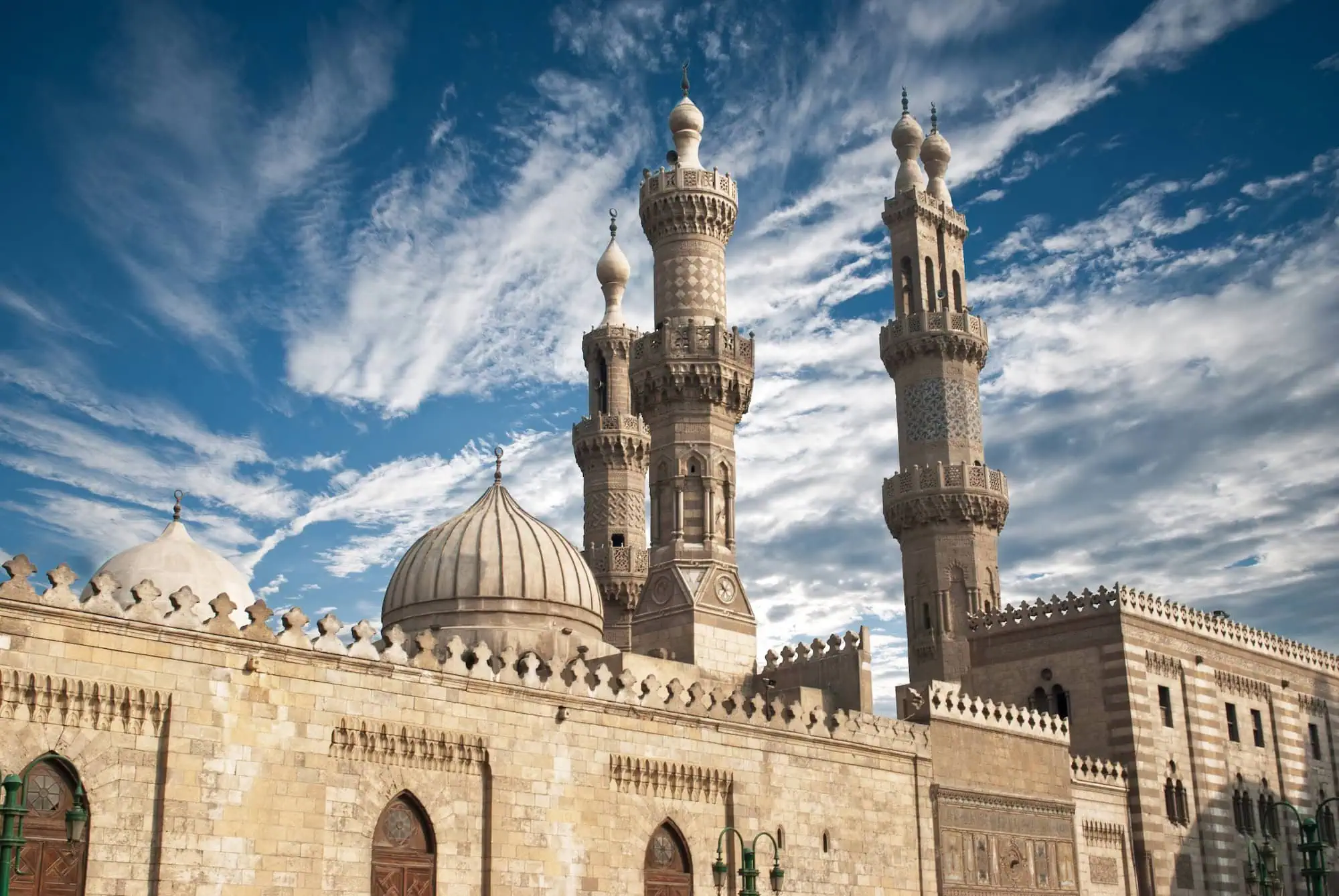 Al-Azhar Mosque in Cairo with distinctive minarets and Islamic architecture against dramatic sky