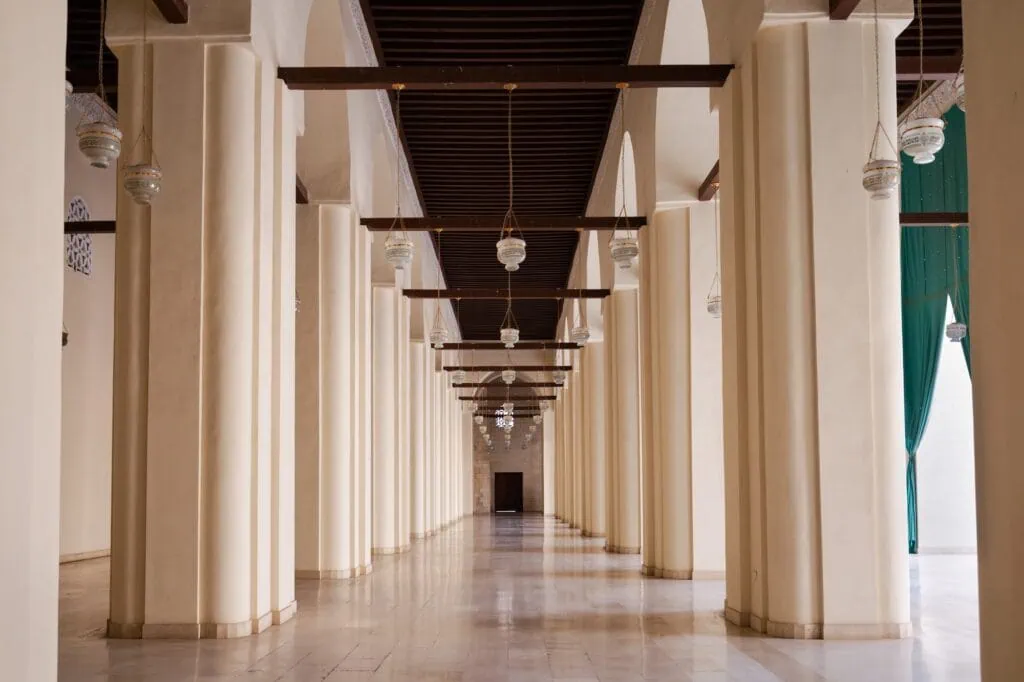 An interior corridor with stone columns, arches, and vaulted ceiling inside the Al-Hakim Mosque, Cairo