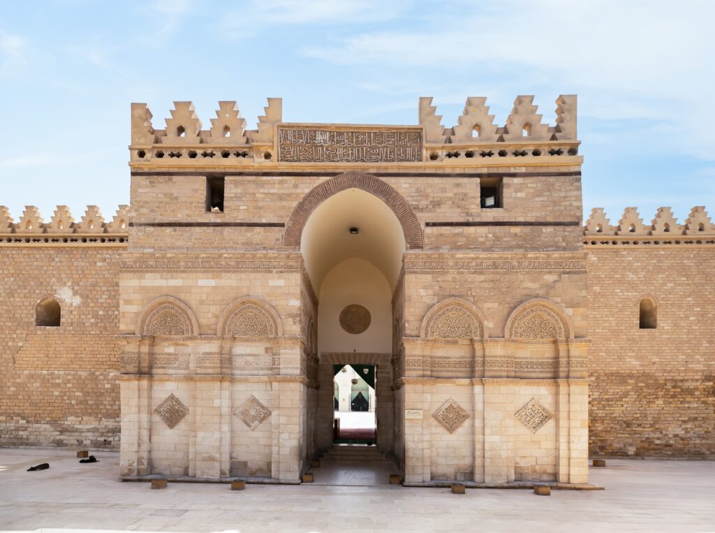 The main entrance with massive stone portal, flanking towers, and carved architectural details at Al-Hakim Mosque, Cairo