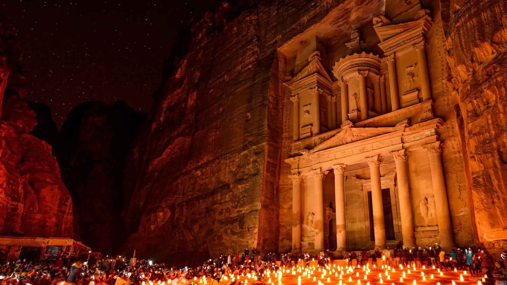 The Treasury at Petra illuminated by candlelight at night with crowds gathering