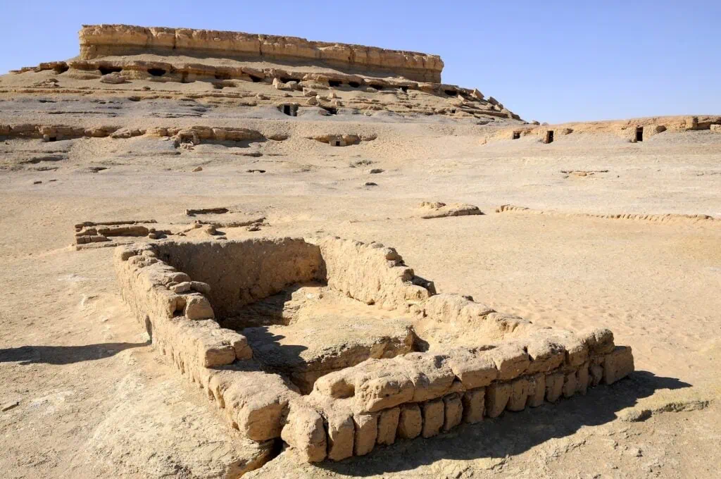 Rock-cut burial chambers and painted tomb entrances at Al Muzawaka Tombs in the desert landscape of Dakhla Oasis, Dakhla Oasis