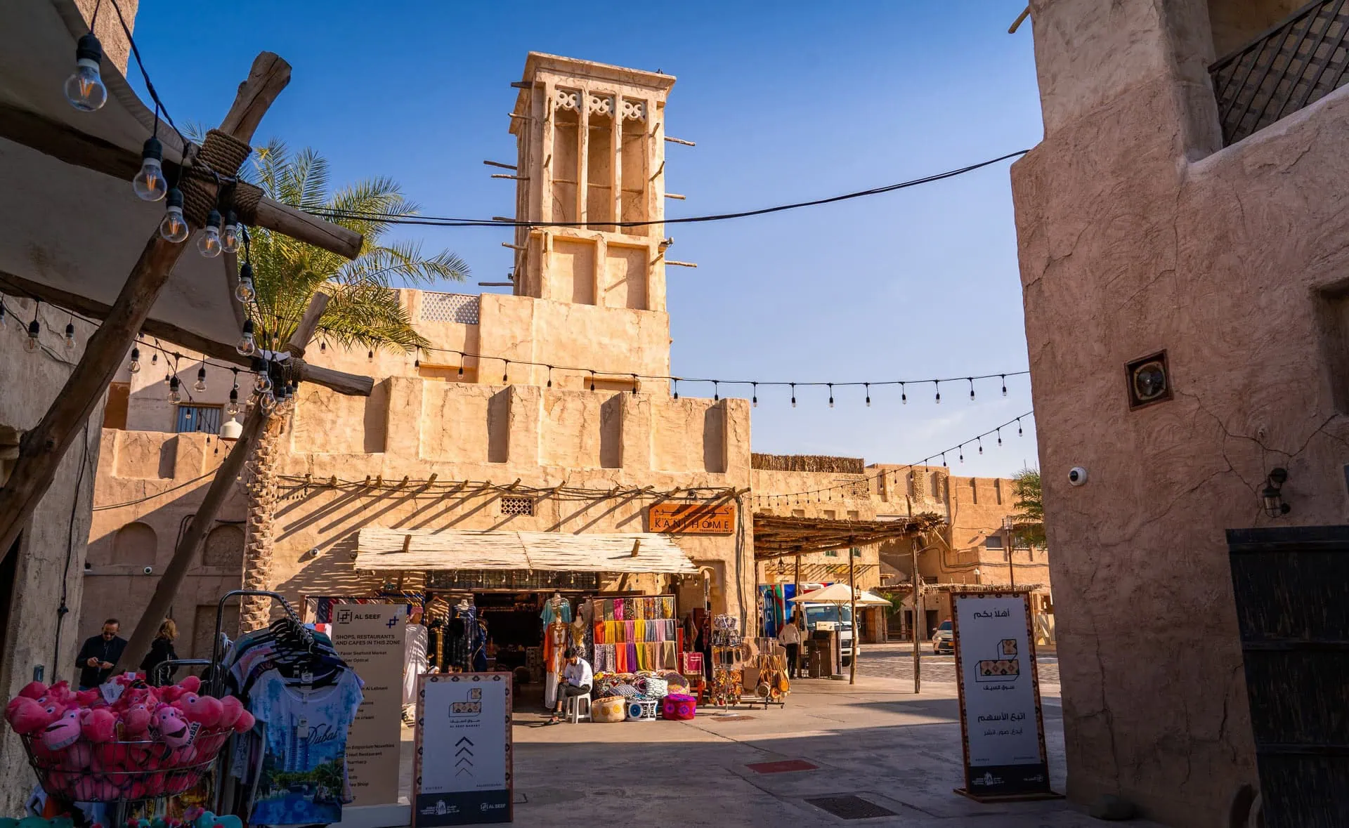 Traditional Arabic marketplace in Al Seef district with wind towers and colorful textiles