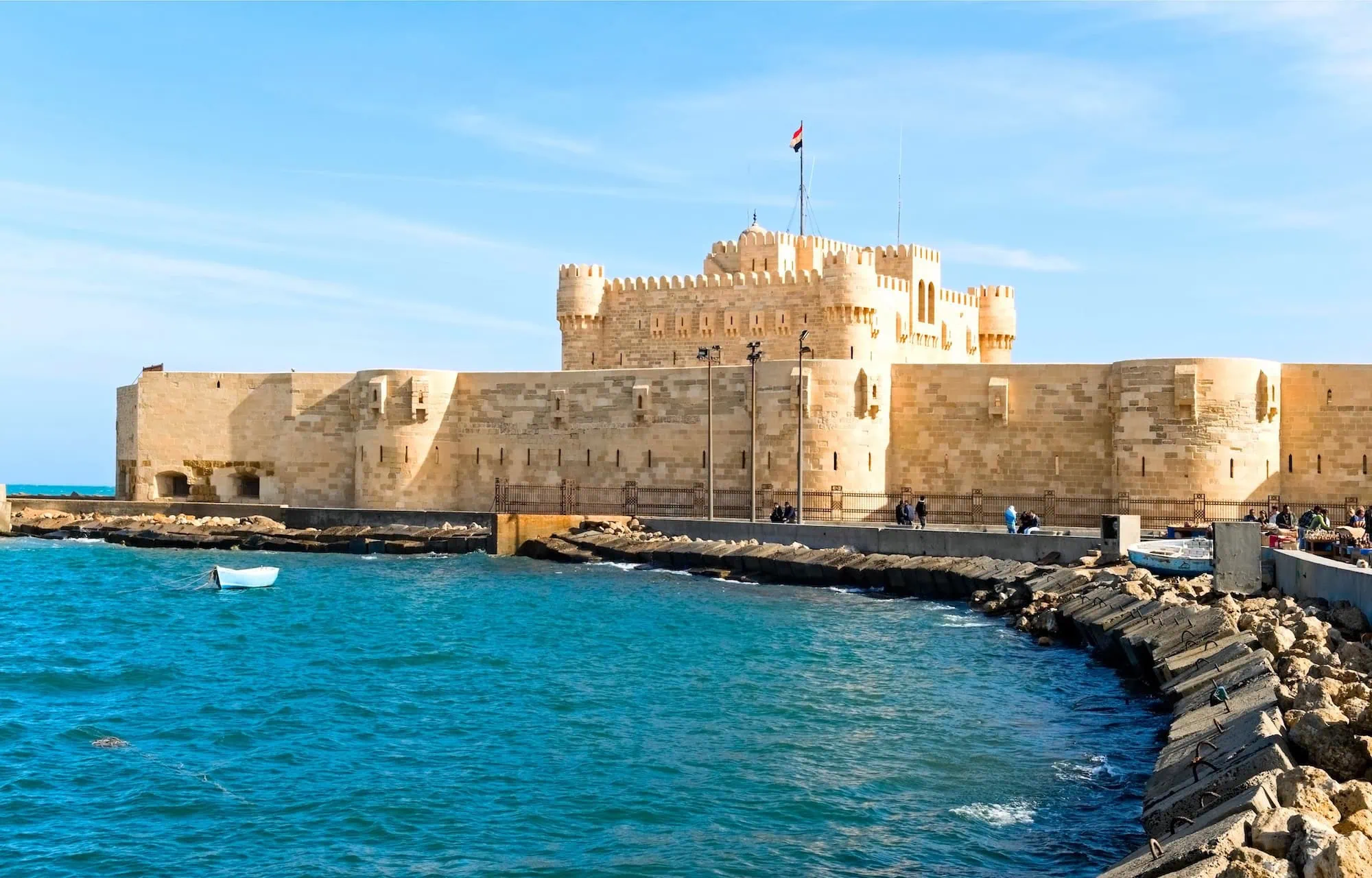 Historic Qaitbay Citadel fortress in Alexandria overlooking Mediterranean harbor with boats and visitors