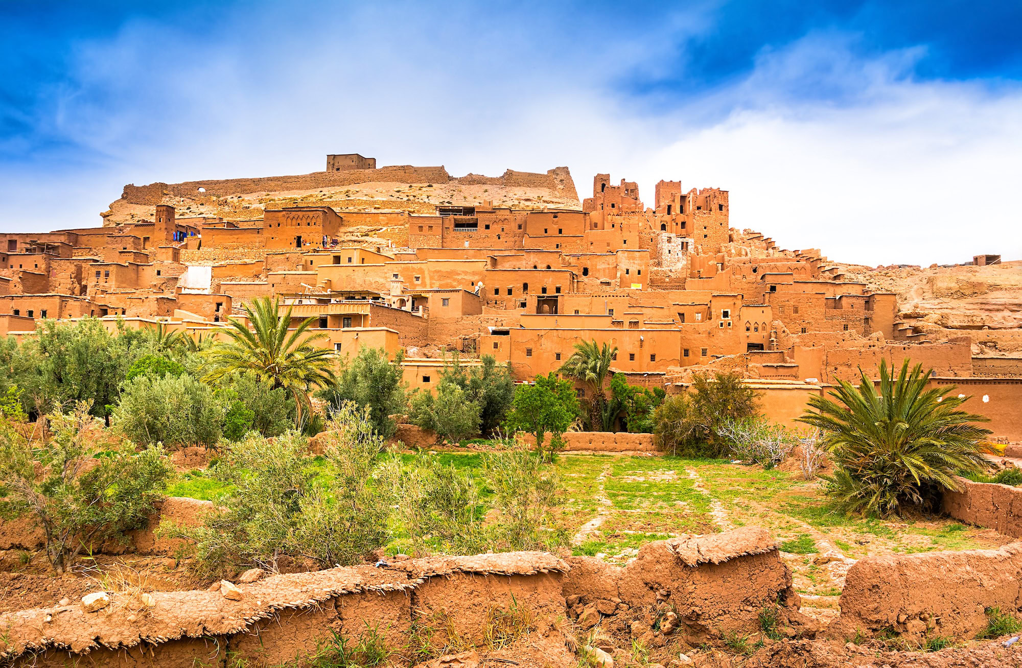 Ait Ben Haddou kasbah fortified village with adobe buildings and palm trees in Morocco desert landscape