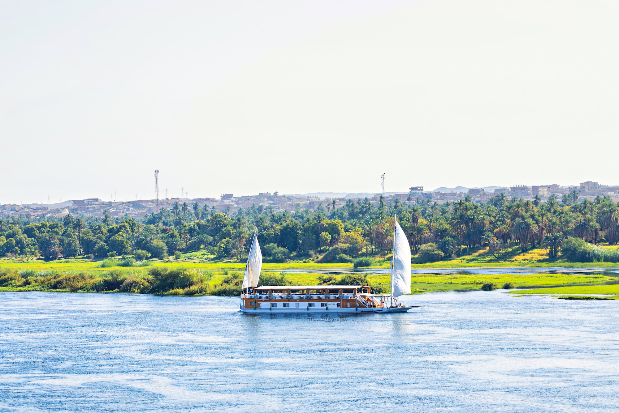 Traditional Egyptian dahabiya sailing boat with white sails on the Nile River