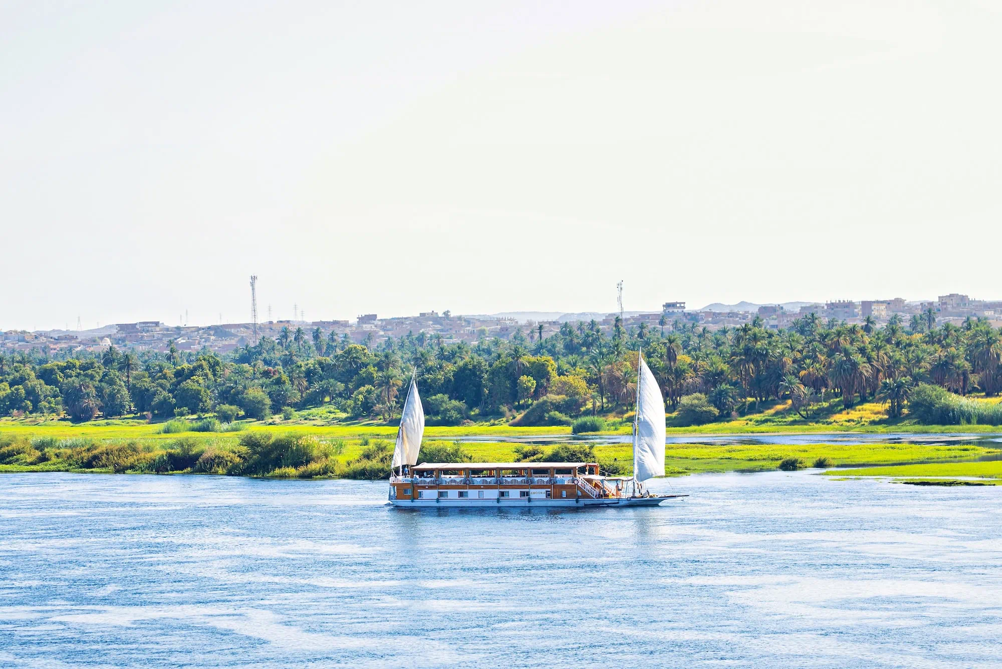 Traditional Egyptian dahabiya sailing boat with white sails on the Nile River