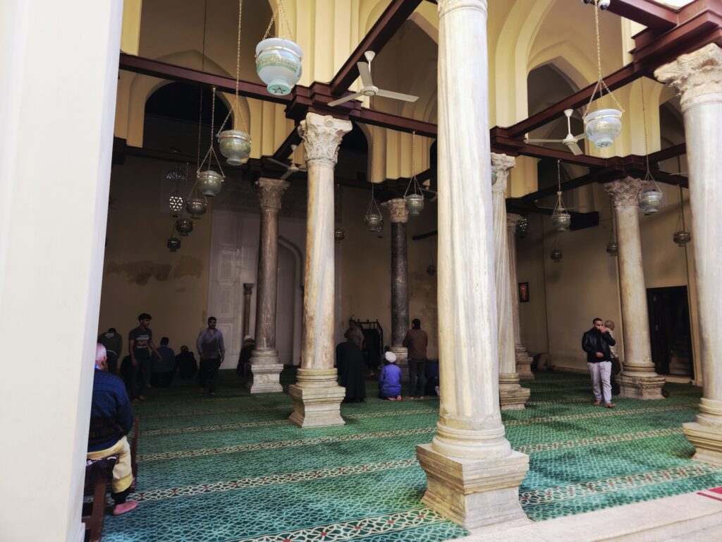 The prayer hall with stone columns, simple arches, and prayer carpets inside the Al-Aqmar Mosque, Cairo