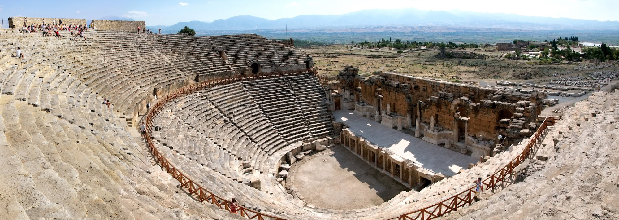 Ancient Roman amphitheater ruins with tiered stone seating and columns at Hierapolis