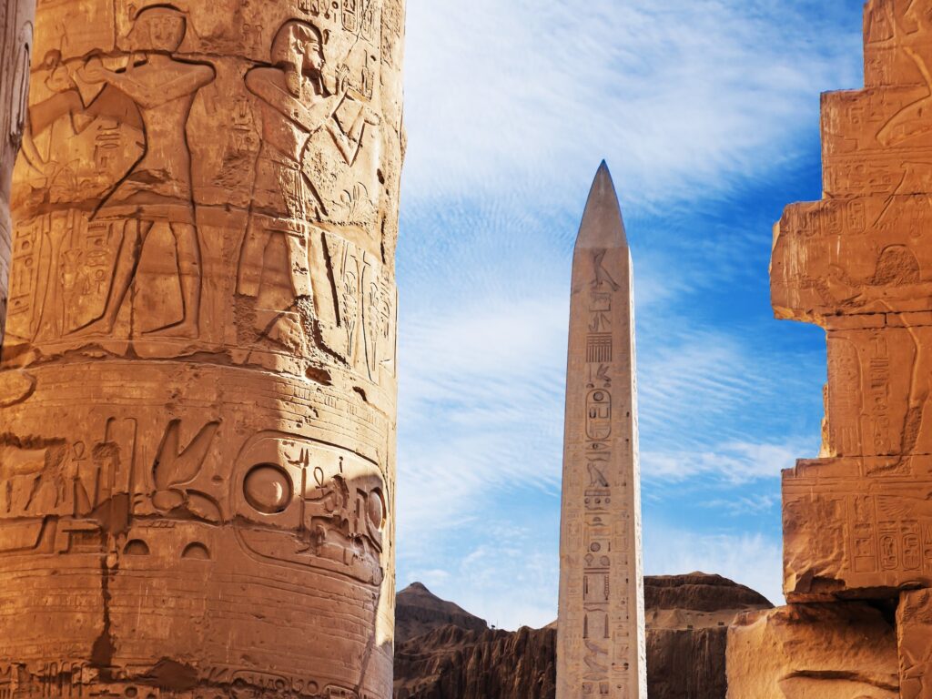 First pylon of Luxor Temple showing an obelisk and seated statues of Ramses II at the entrance, Luxor