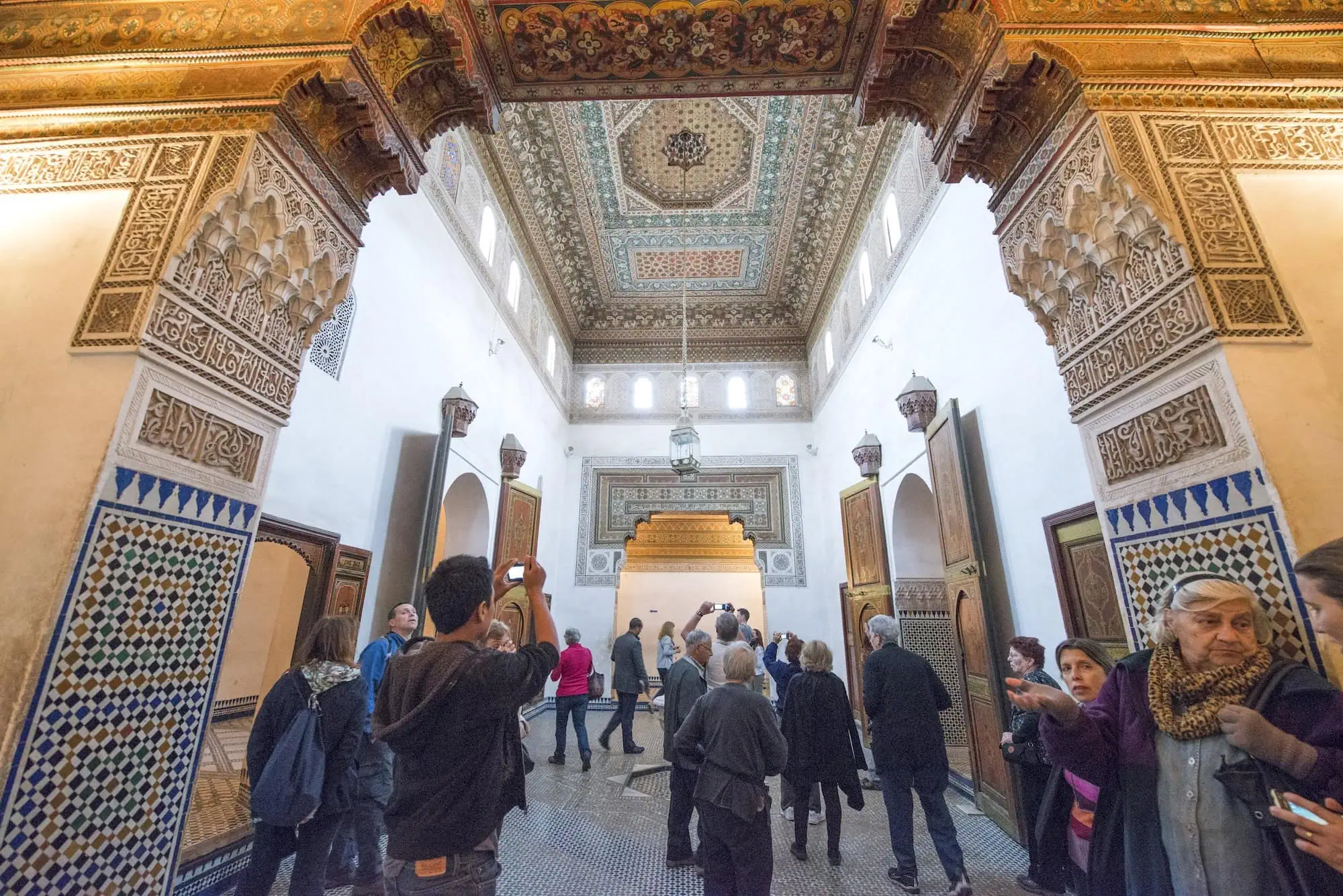 Ornate hall in Bahia Palace featuring traditional Moroccan Islamic architecture with carved arches and colorful tilework