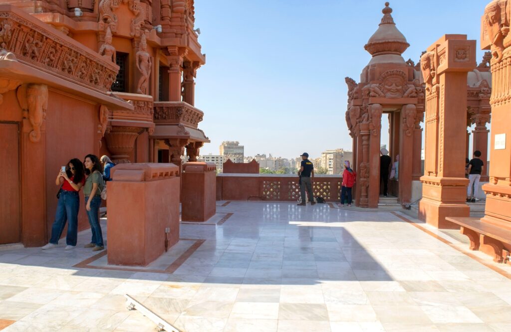 A daytime city view from the rooftop of the Baron Empain Palace with visitors walking along the temple-style terrace, Cairo