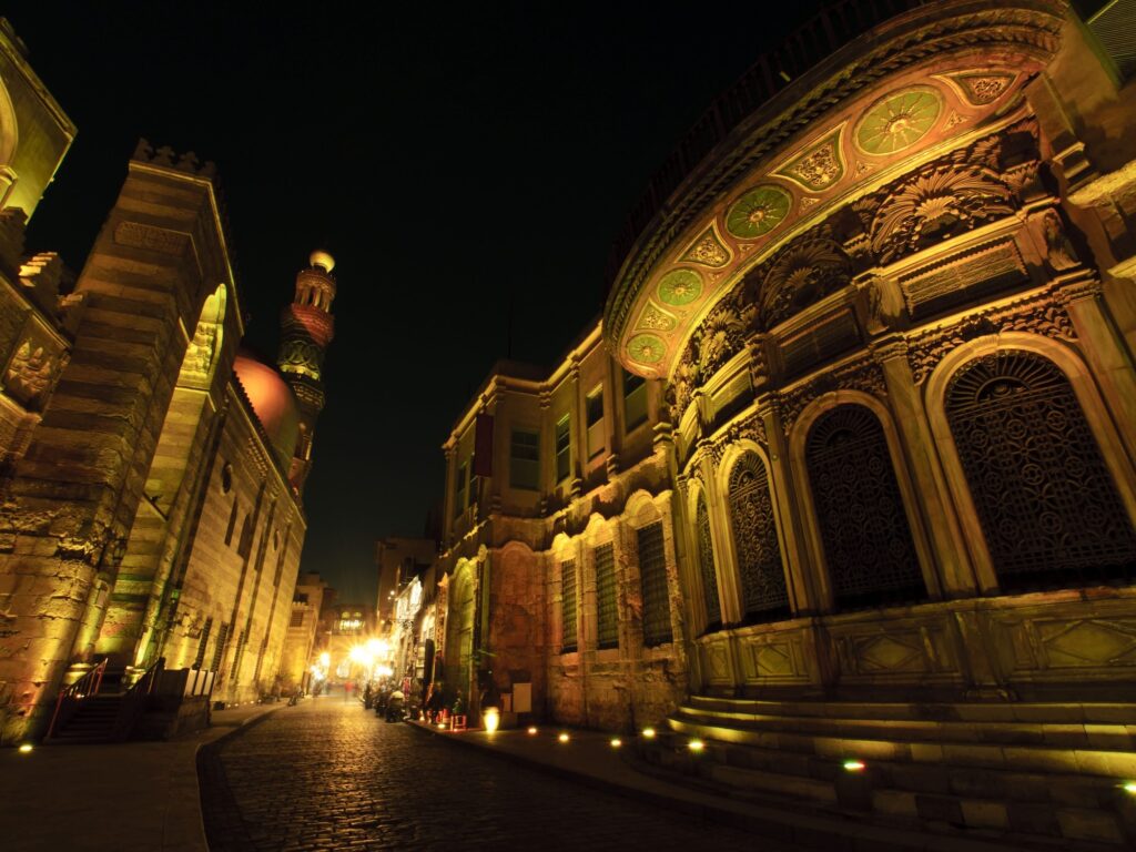 Historic Islamic Cairo buildings illuminated at night with mosque domes and minarets, Cairo