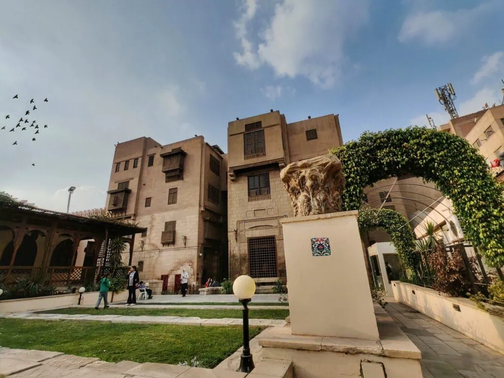 A landscaped garden with pathways, trees, and surrounding historic stone buildings outside the Gayer-Anderson Museum, Cairo