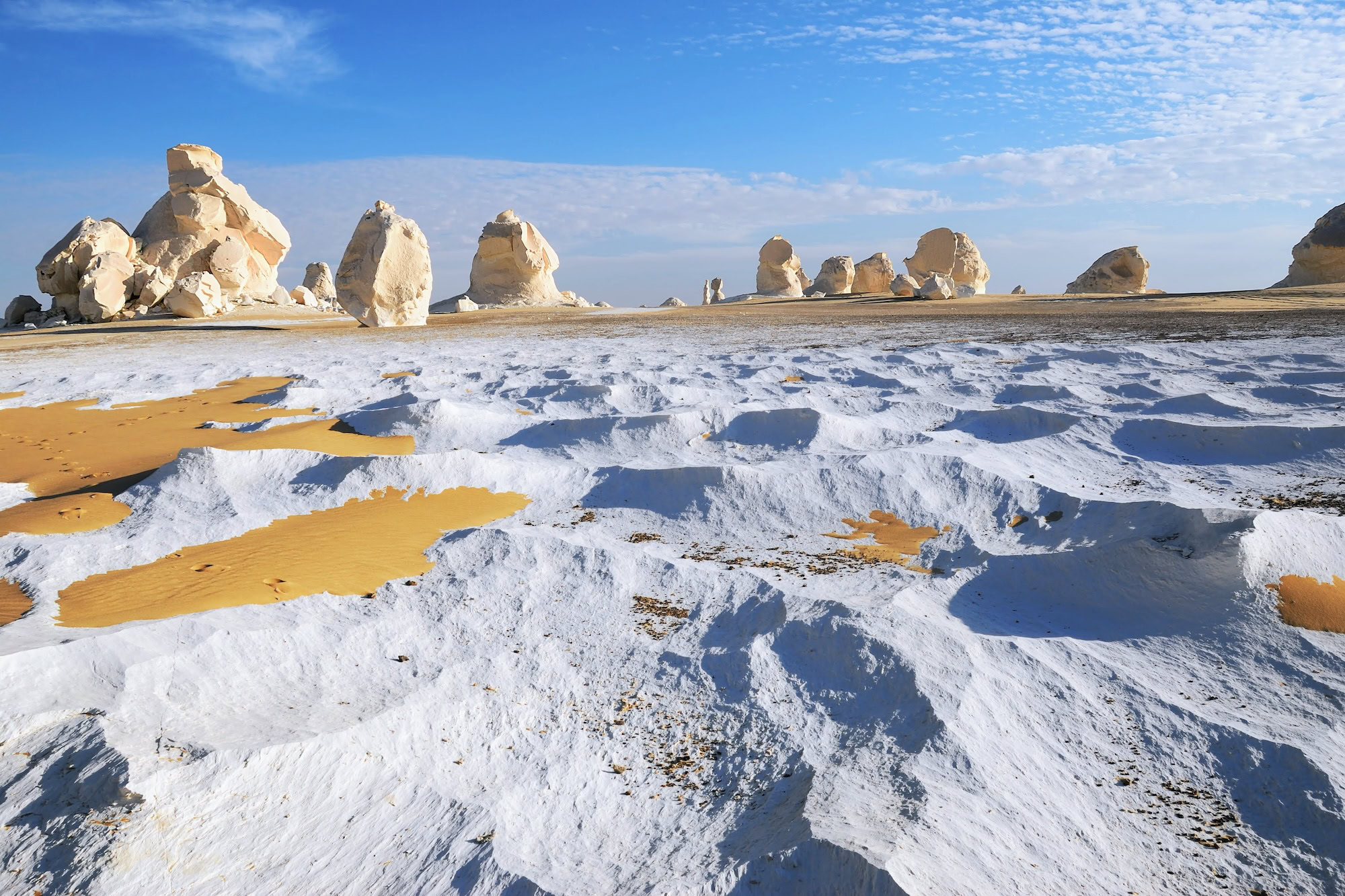 Surreal white limestone formations in Egypt's White Desert against blue sky