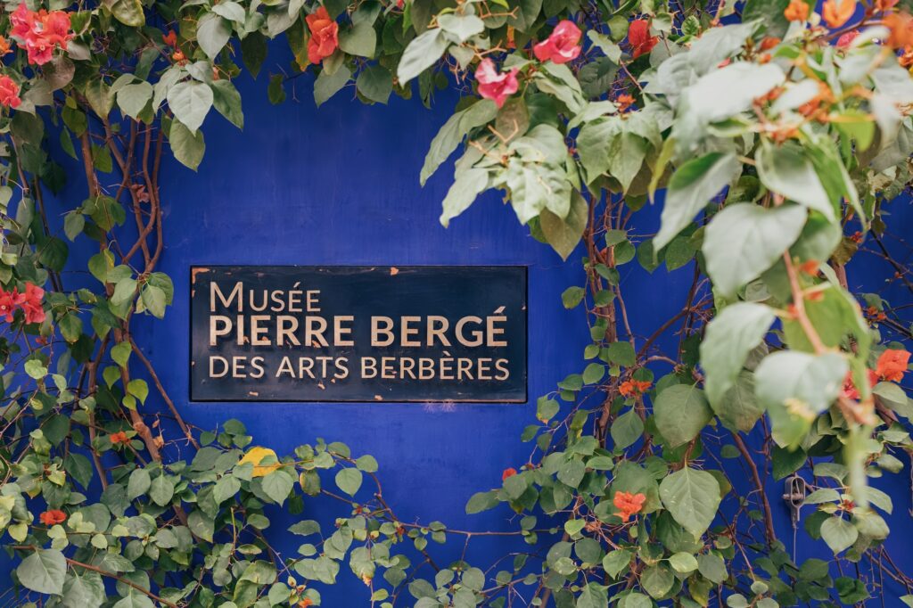 Bougainvillea growing on a bright blue wall with the sign of the Musee Pierre Berge des Arts Berberes