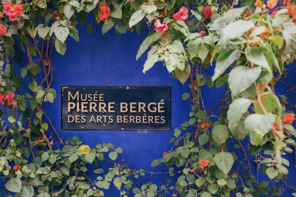 Bougainvillea growing on a bright blue wall with the sign of the Musee Pierre Berge des Arts Berberes