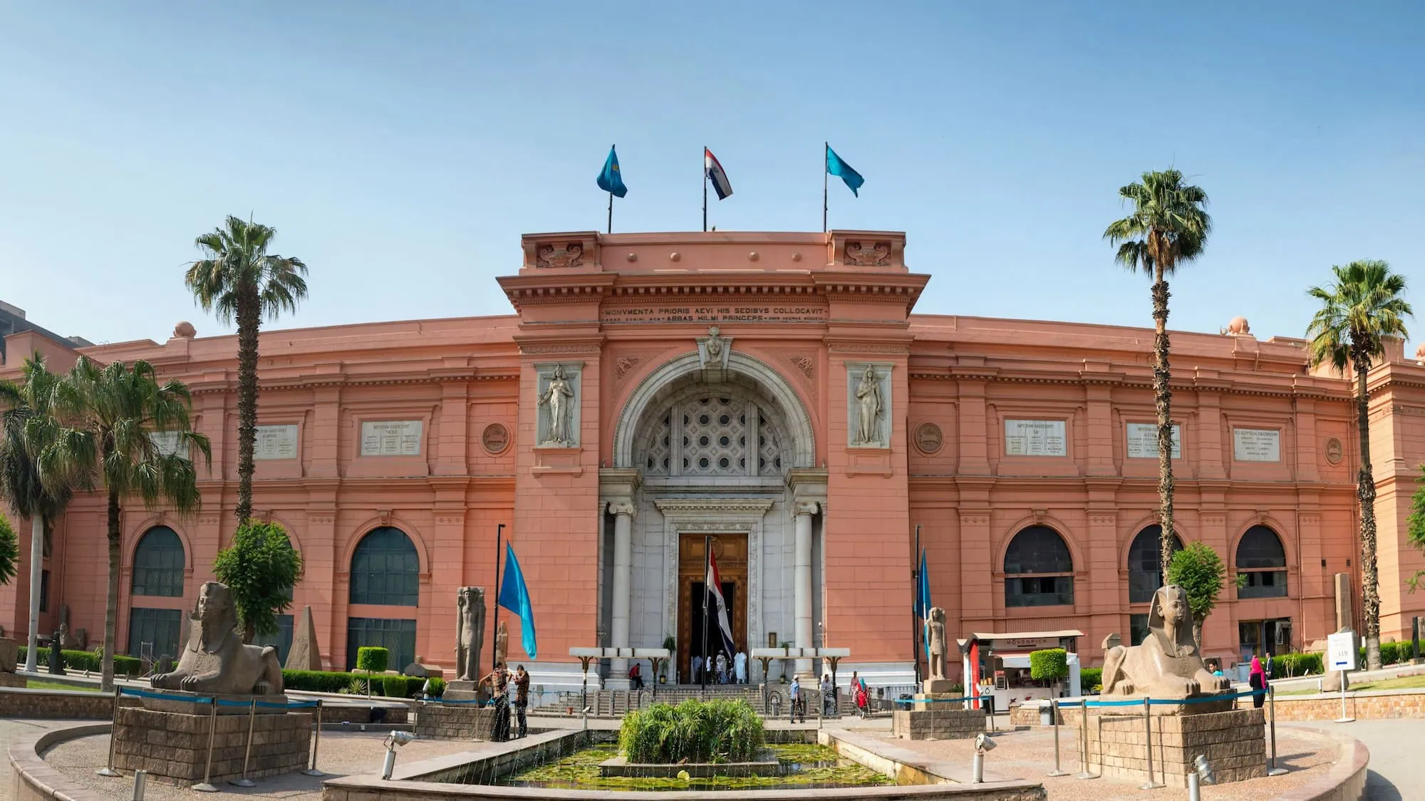 Egyptian Museum building with palm trees and tourists in courtyard