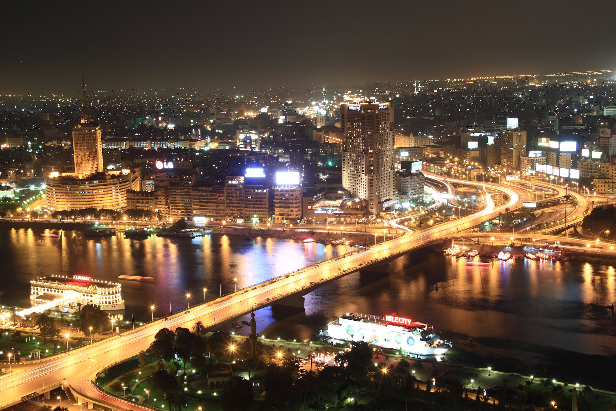 Cairo cityscape at night with the Nile River, illuminated bridges, and modern skyscrapers