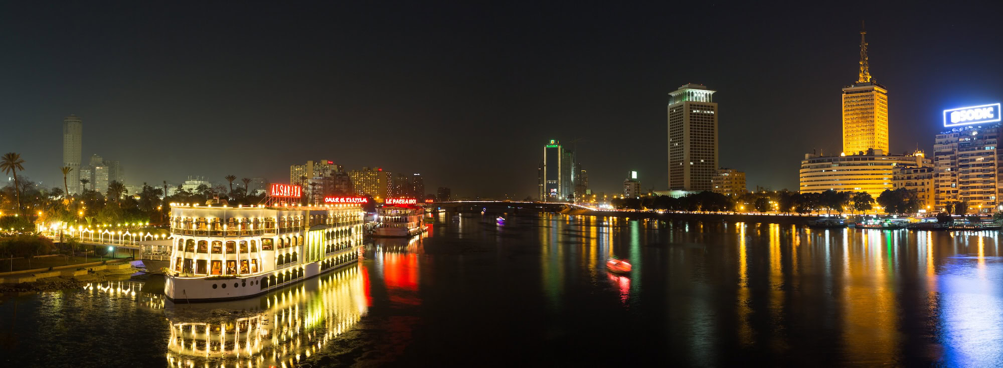 Illuminated riverboat on the Nile with Cairo skyline and modern buildings
