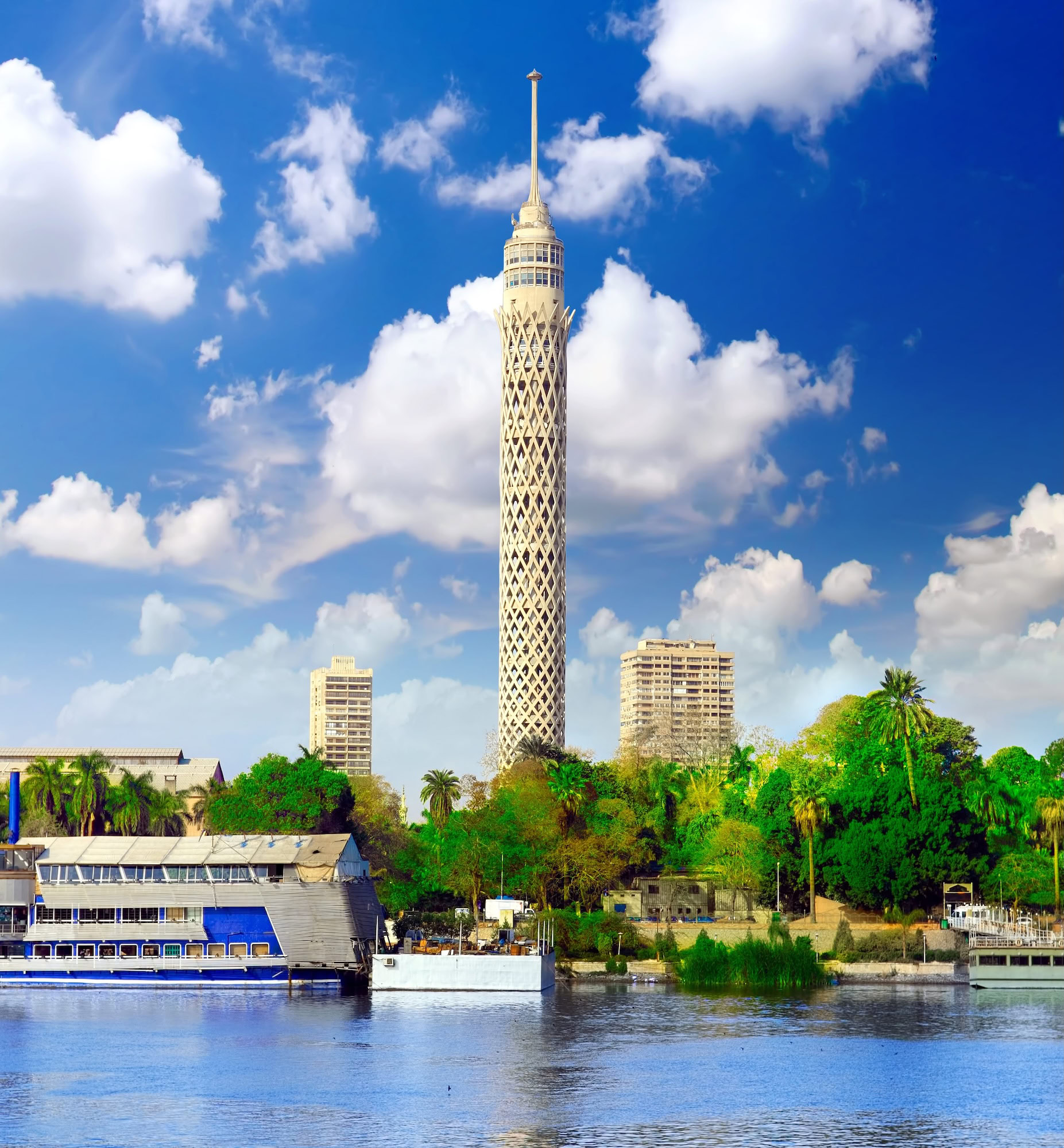 Cairo Tower rising above the Nile River with surrounding buildings and palm trees