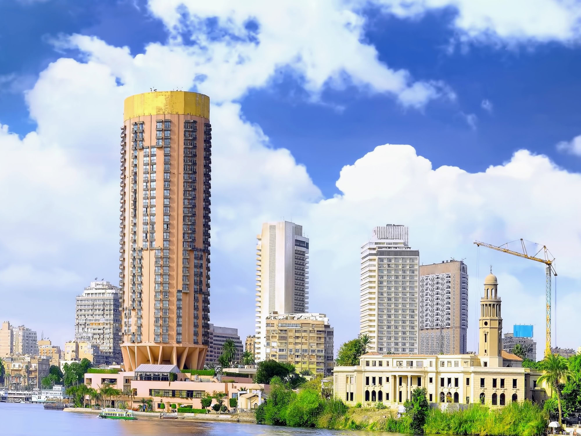 Modern Cairo waterfront with high-rise buildings and Nile River boats showing transportation options