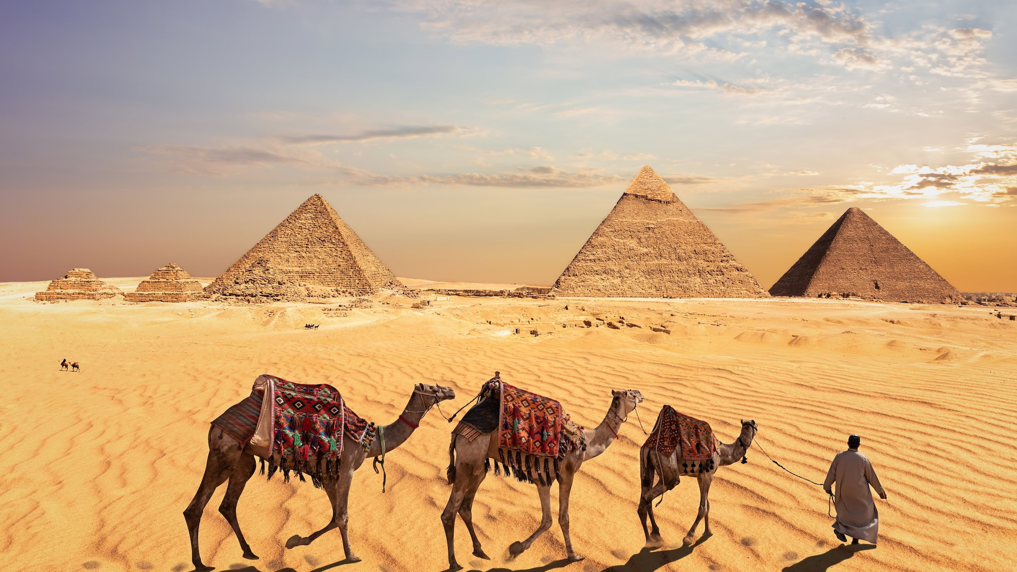 Great Pyramids of Giza with camels and handlers in desert landscape