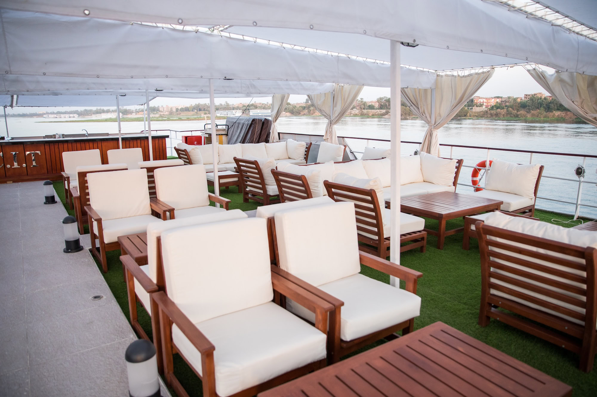 Luxurious deck of Nile River cruise ship with comfortable lounge chairs and canopy