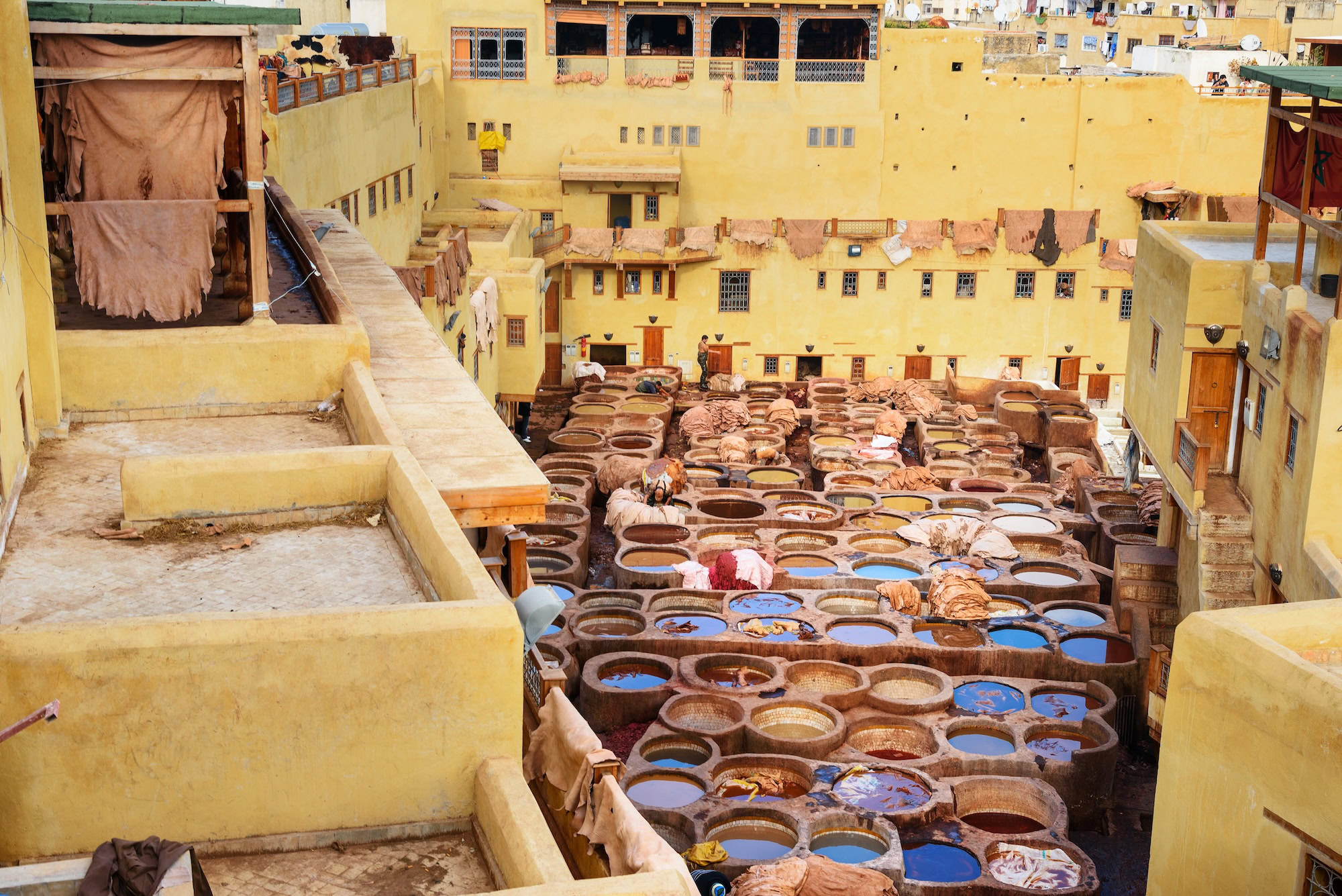 Traditional leather tannery vats in Fez medina with colorful dyes and drying hides