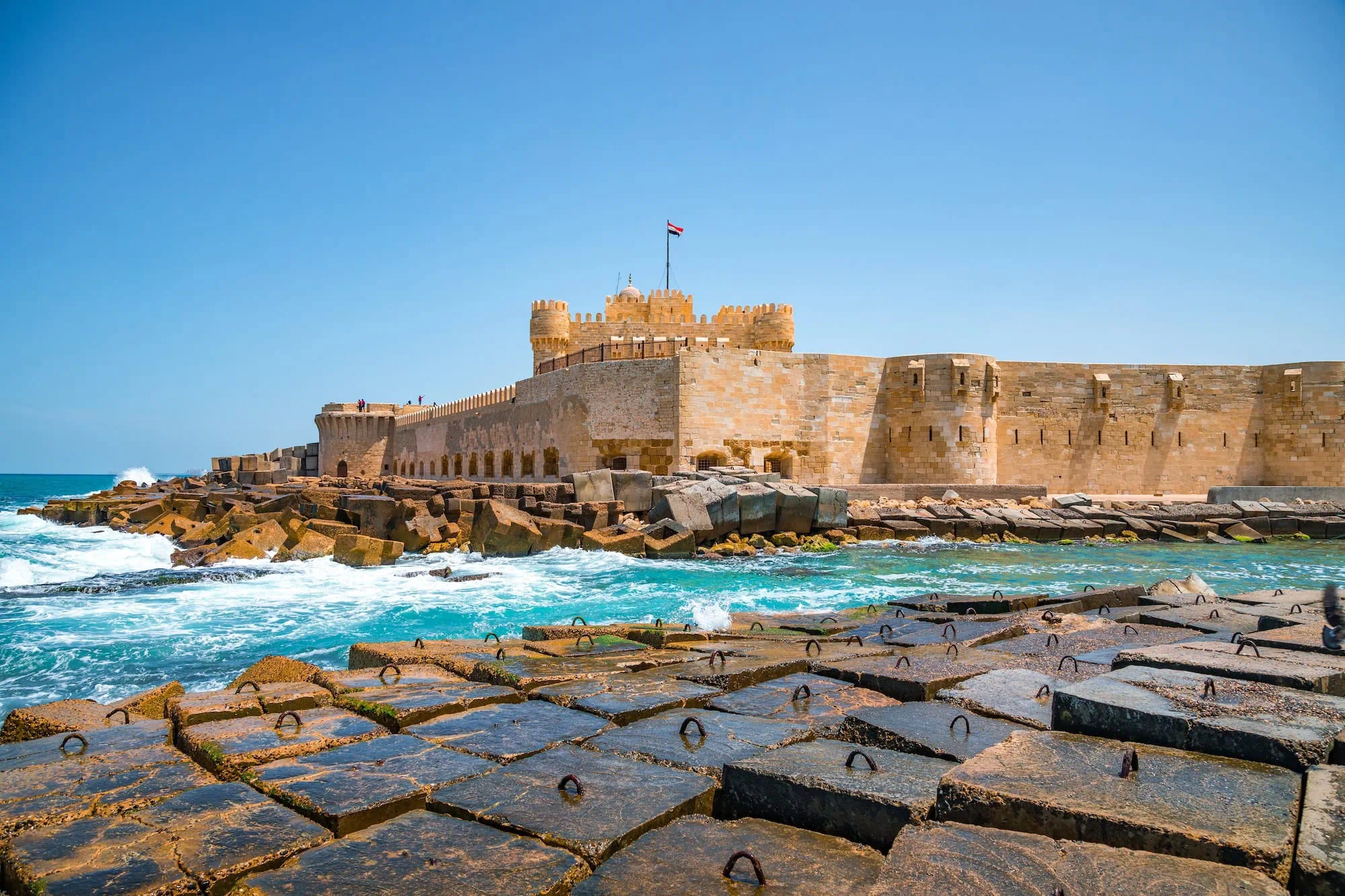 Citadel of Qaitbay fortress standing on rocky coastline with Mediterranean Sea waves
