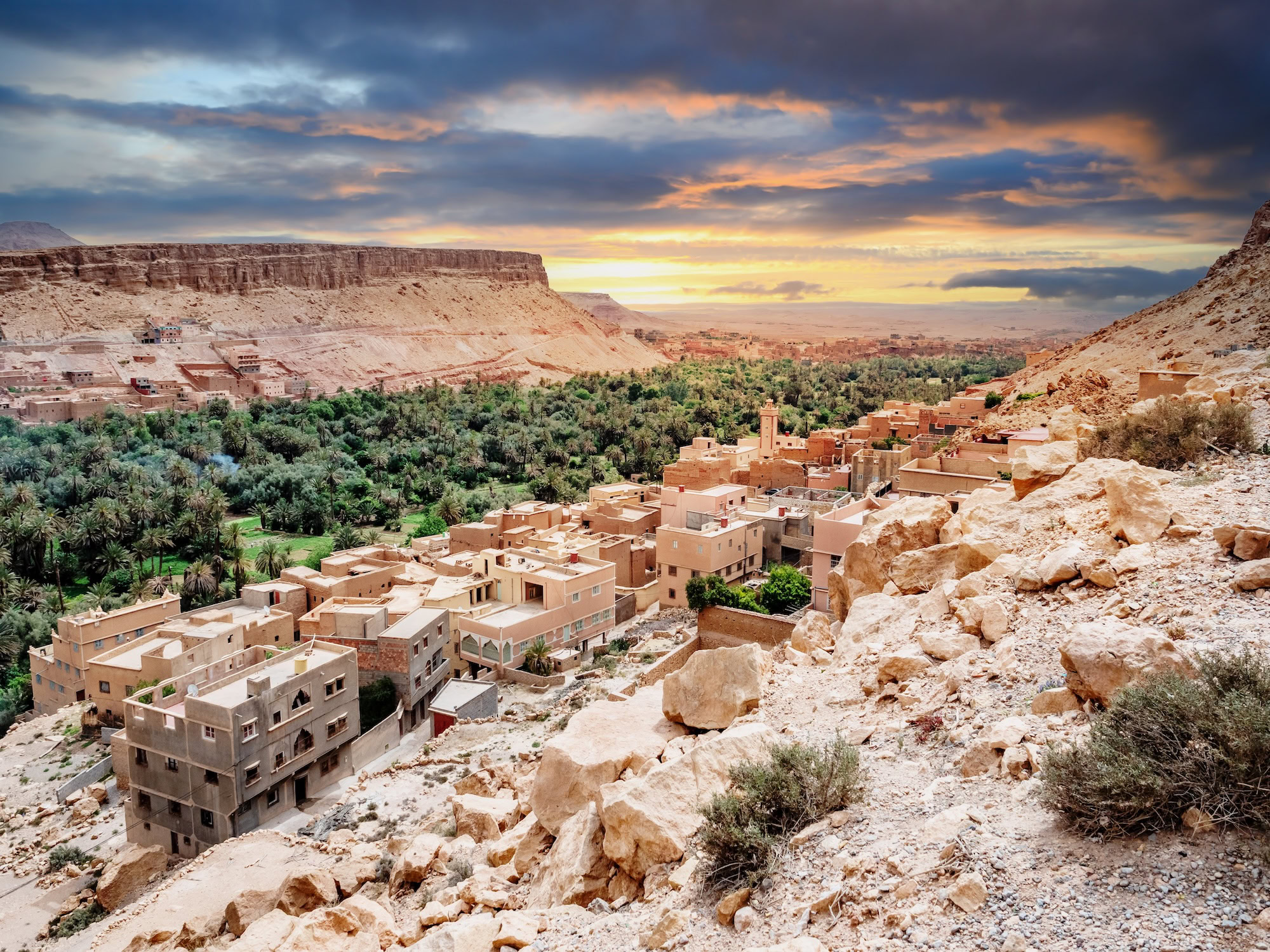Sahara Desert oasis village with traditional clay buildings and palm trees